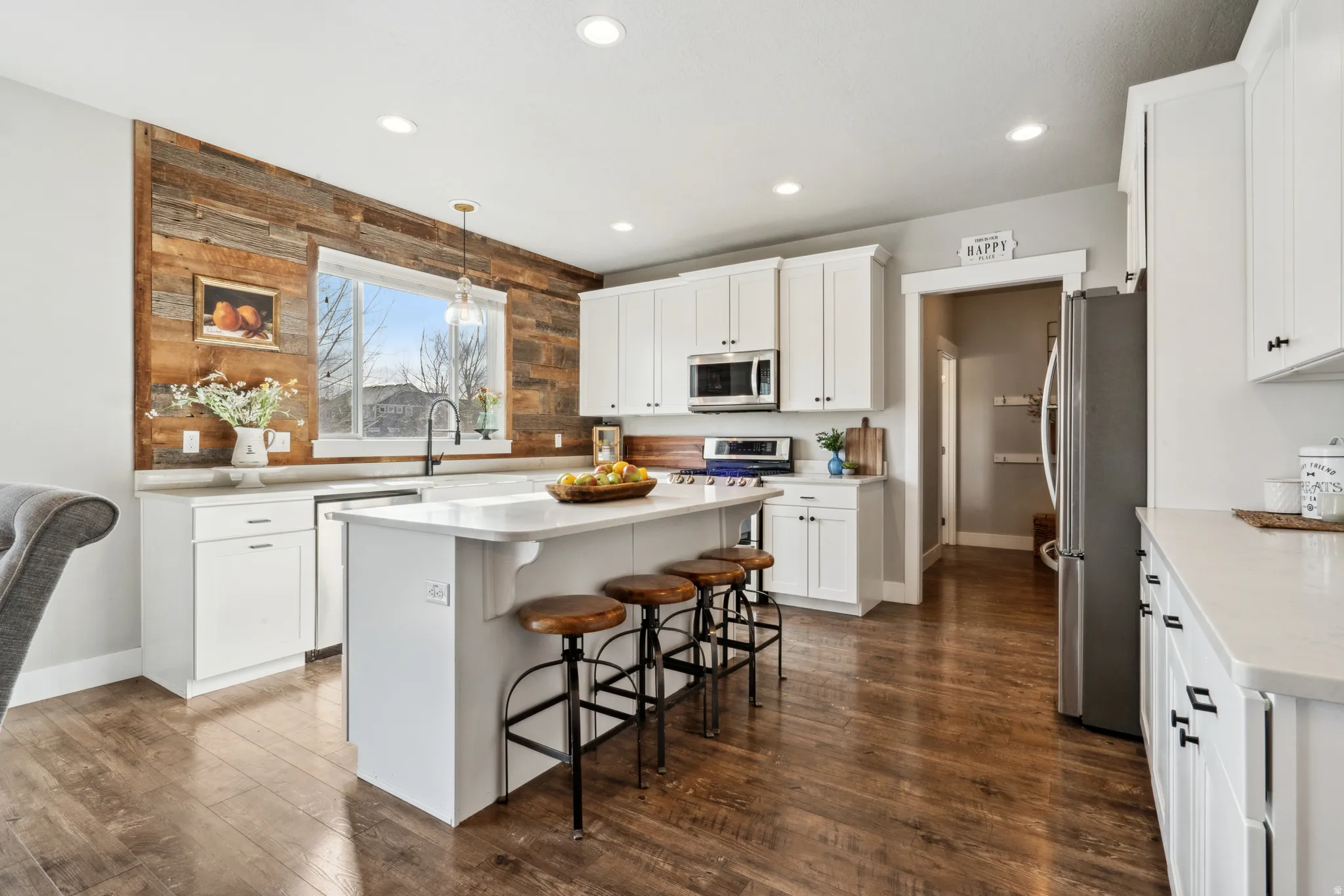 Kitchen with a kitchen bar, white cabinets, appliances with stainless steel finishes, a kitchen island, and recessed lighting