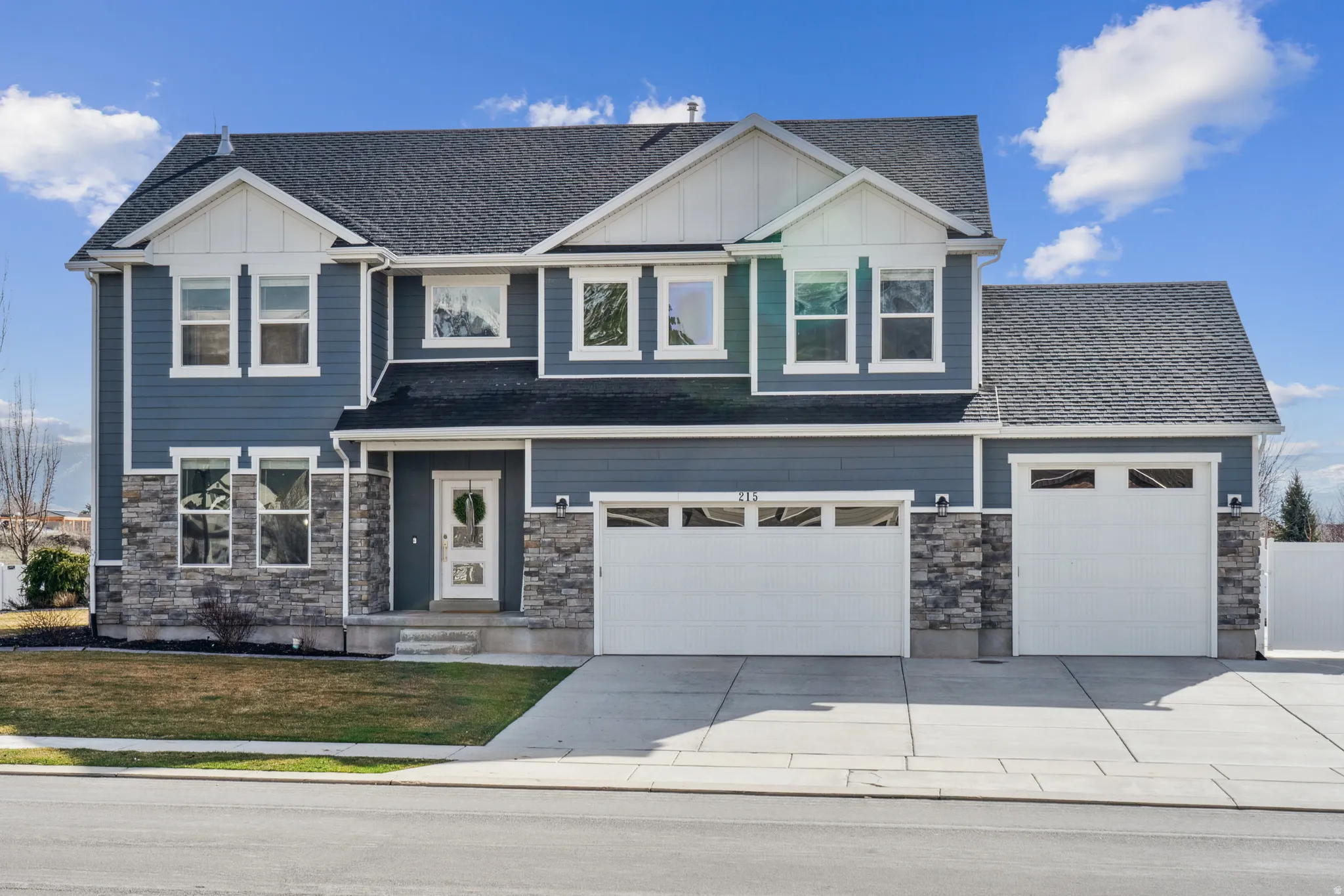 Craftsman-style home featuring board and batten siding, stone siding, driveway, and a front yard