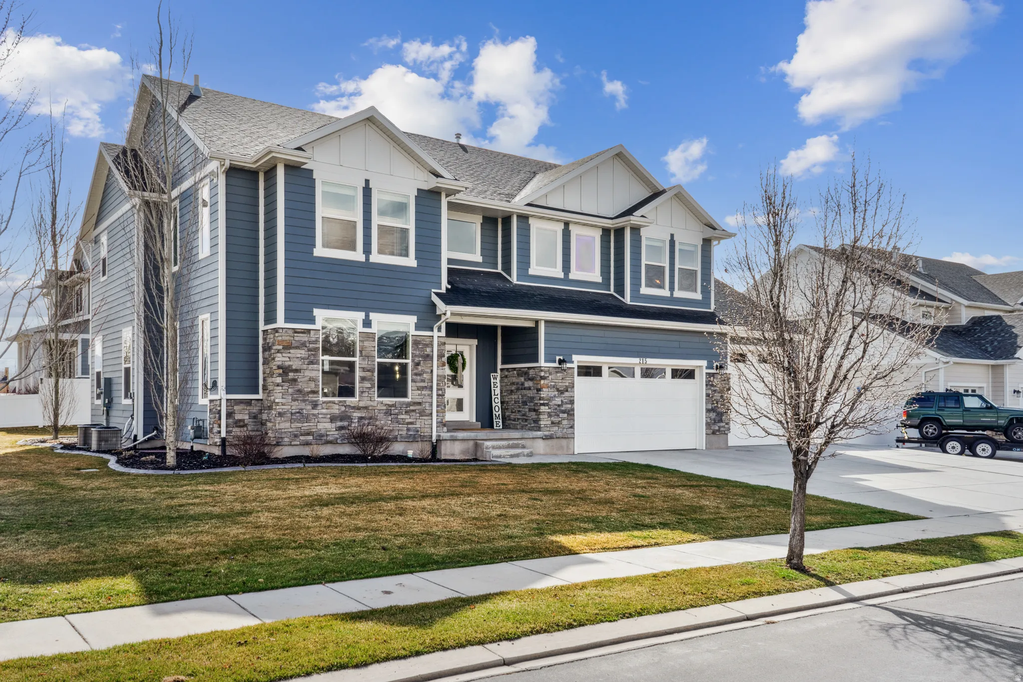 Craftsman house featuring board and batten siding, stone siding, driveway, a front yard, and an attached garage
