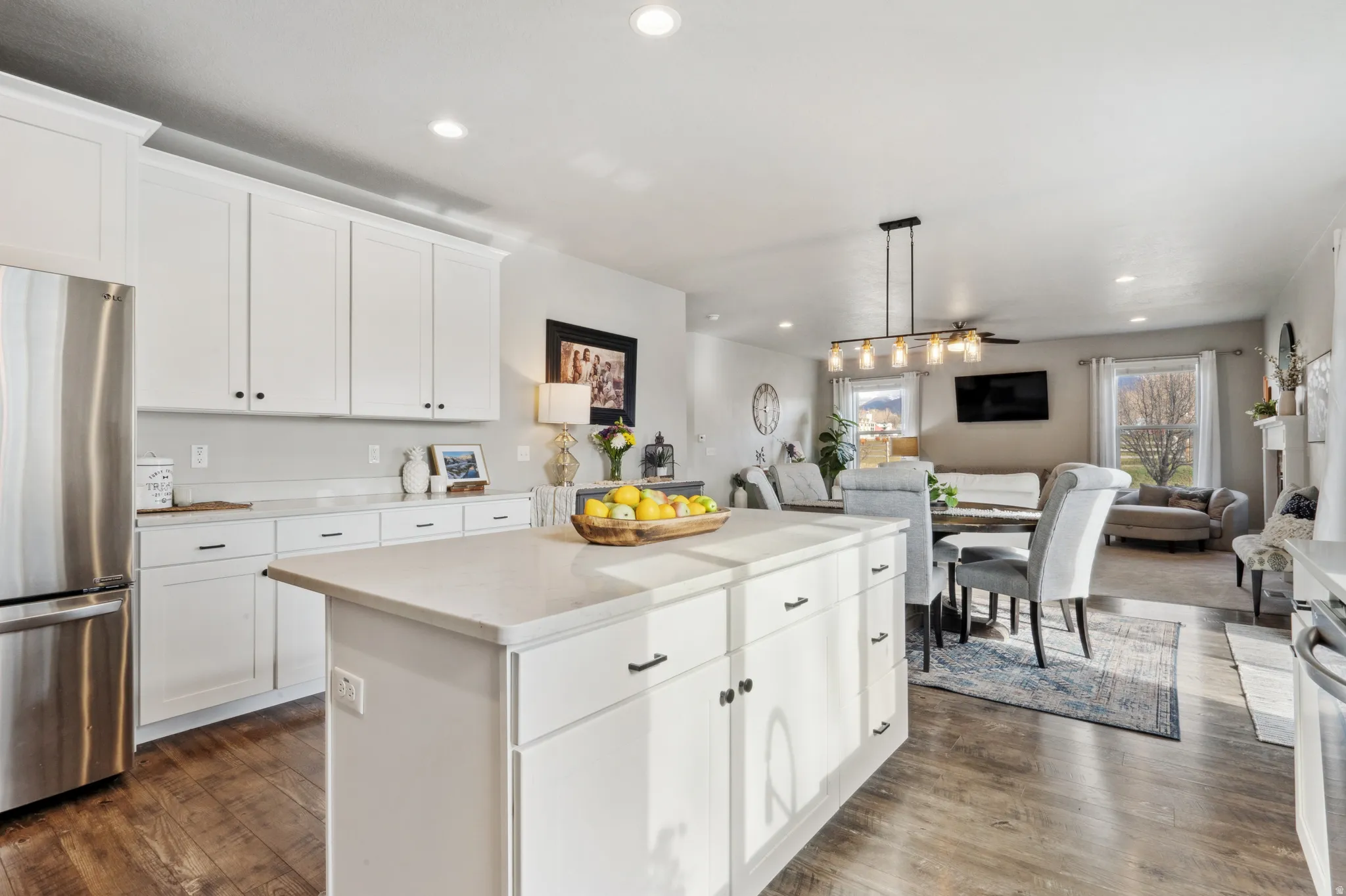 Kitchen with white cabinets, appliances with stainless steel finishes, hanging light fixtures, open floor plan, and recessed lighting