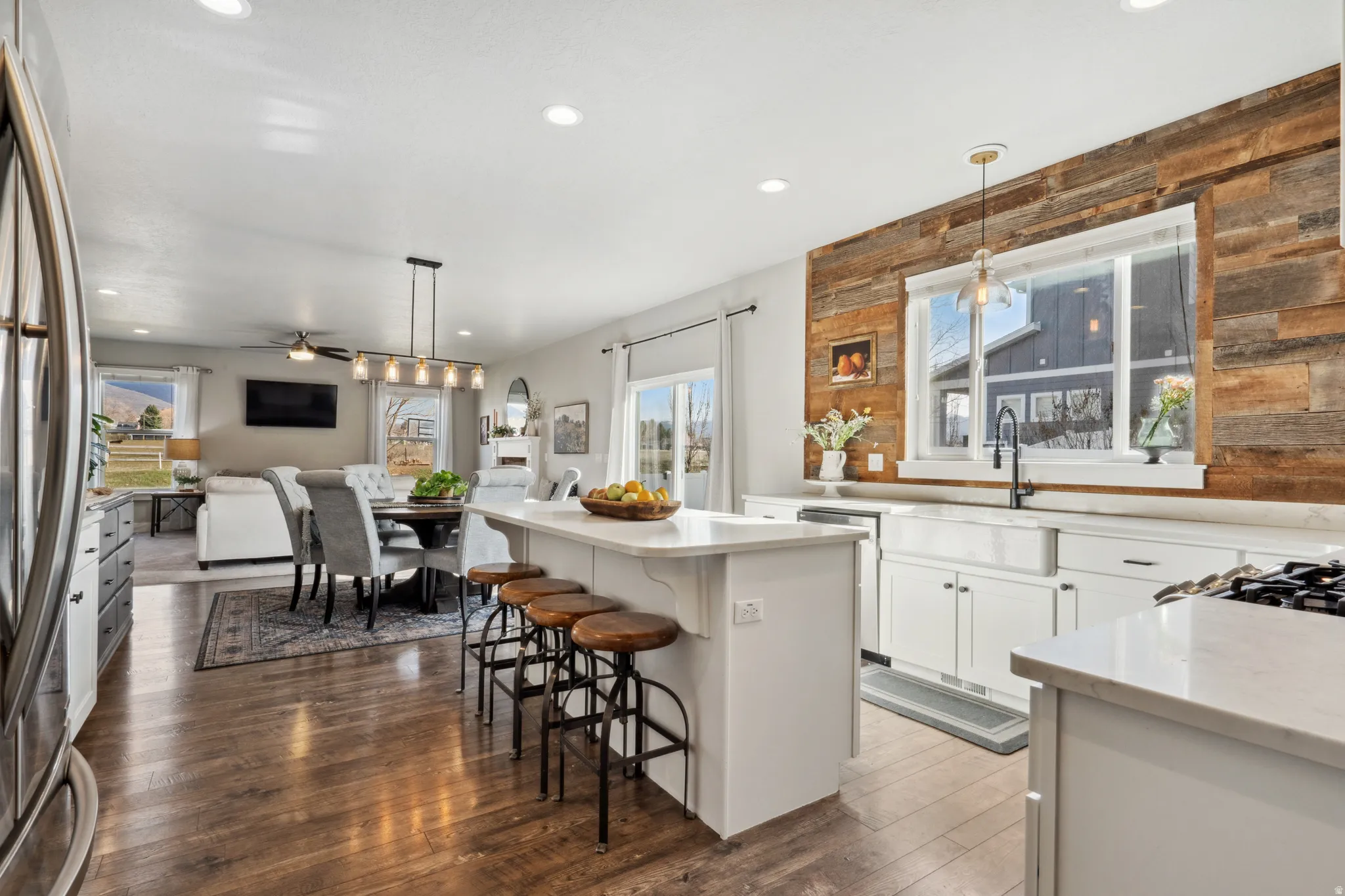 Kitchen featuring hanging light fixtures, white cabinets, dark wood-style floors, a center island, and stainless steel refrigerator