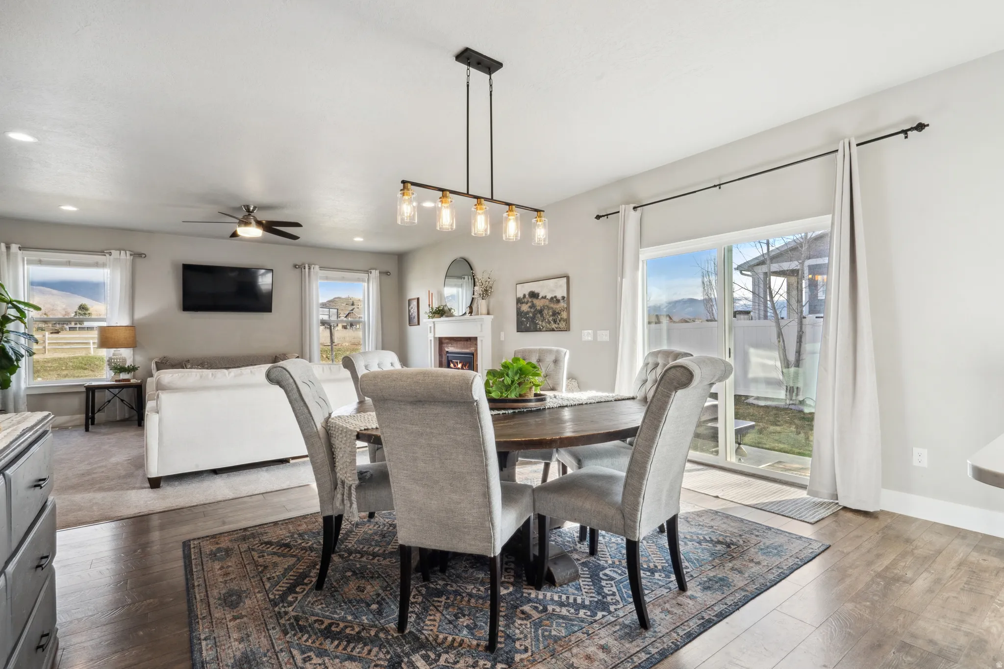 Dining space with dark wood finished floors, a warm lit fireplace, plenty of natural light, and recessed lighting