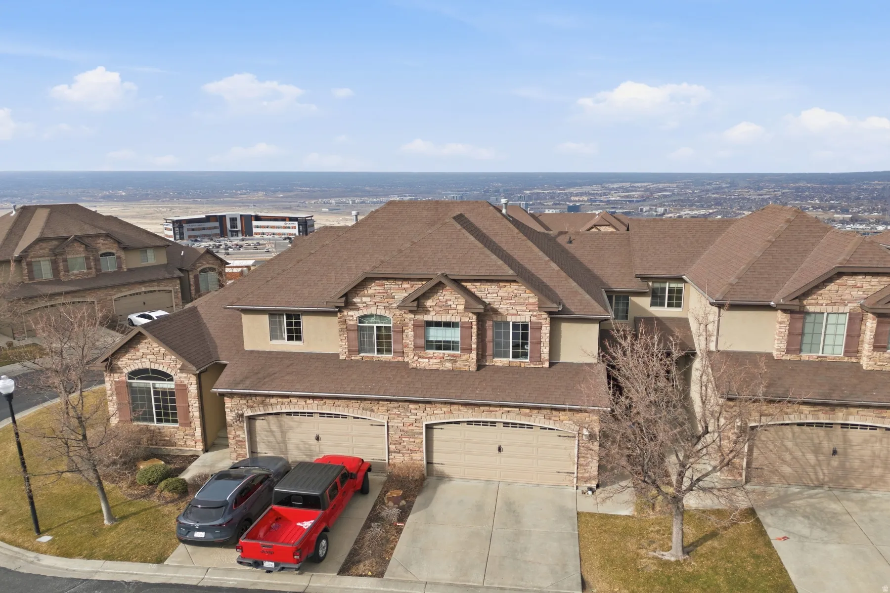 French country style house with stone siding, roof with shingles, concrete driveway, a garage, and a residential view