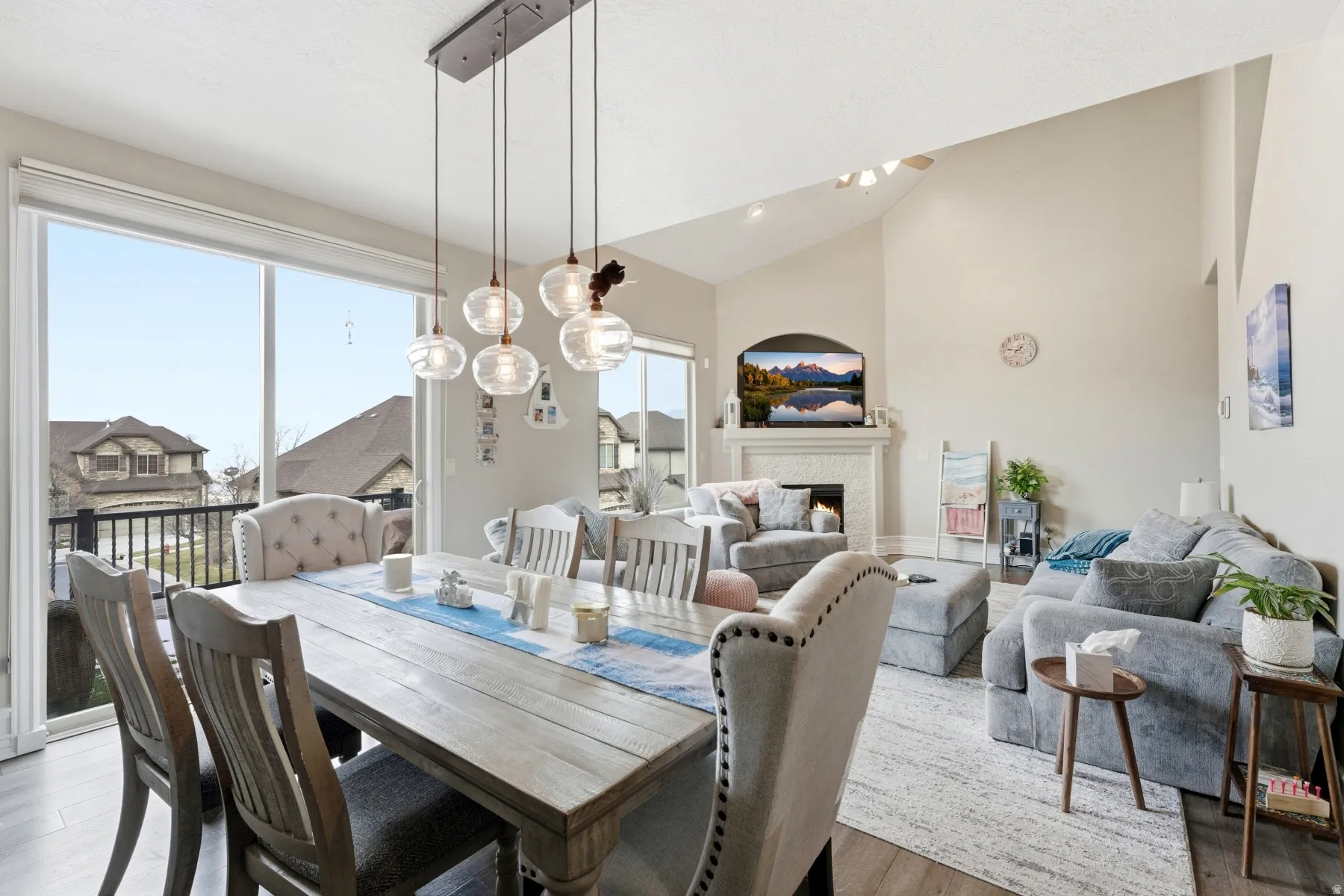 Dining area featuring wood finished floors, a glass covered fireplace, and high vaulted ceiling
