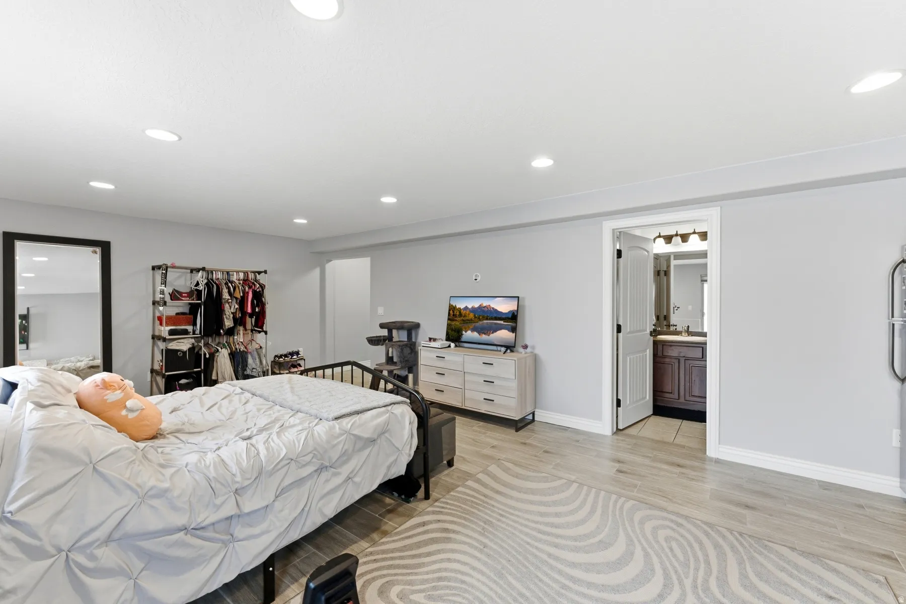 Bedroom with wood finish floors, ensuite bathroom, and recessed lighting