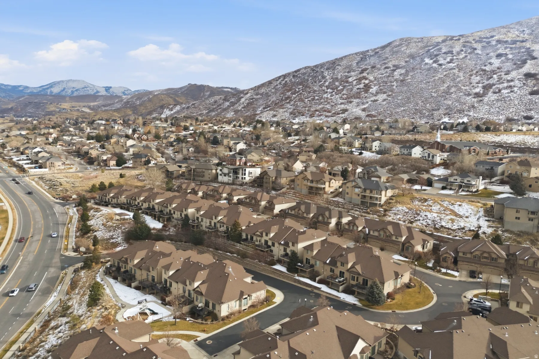 Aerial view of property and surrounding area featuring nearby suburban area and a mountain backdrop