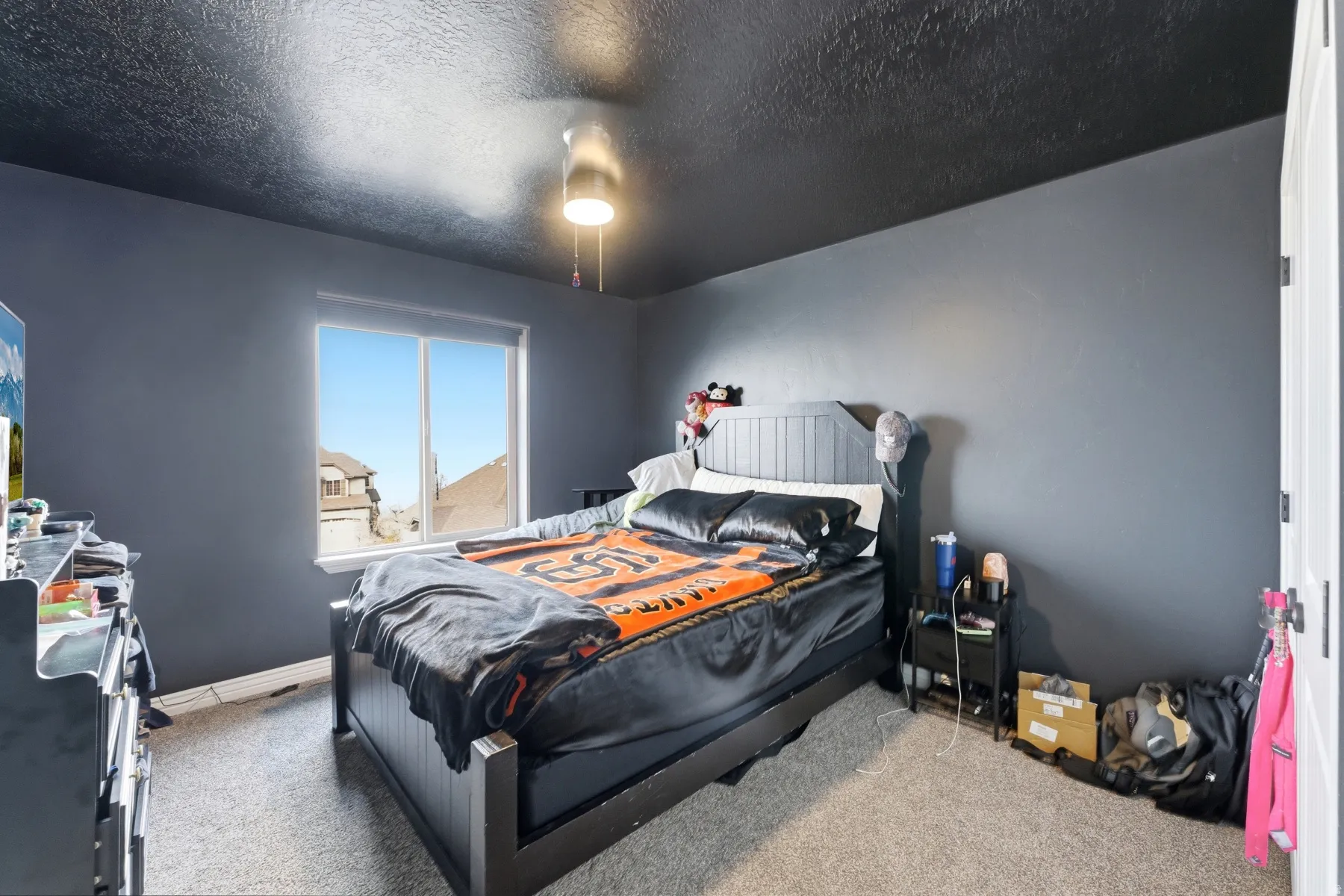 Carpeted bedroom featuring a textured ceiling and baseboards