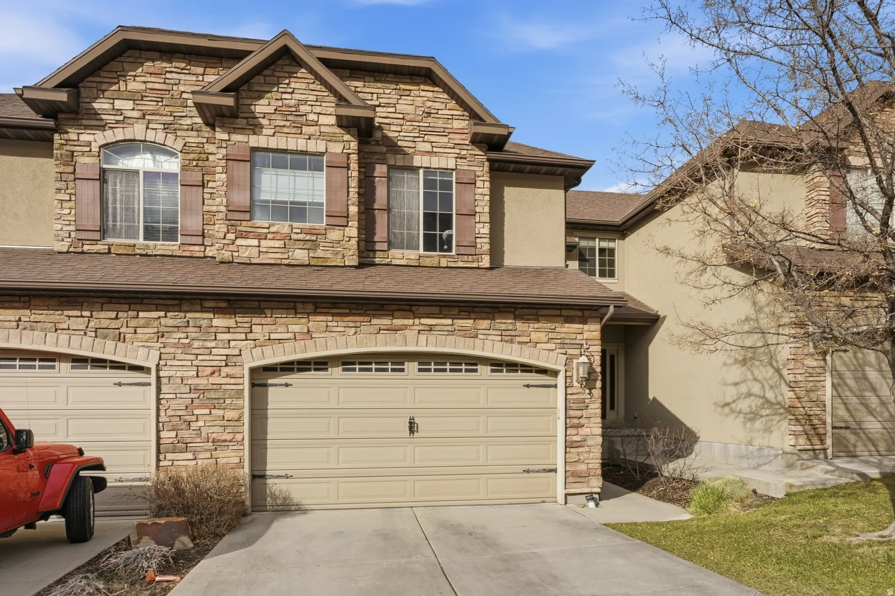View of front of home with stone siding, stucco siding, concrete driveway, and roof with shingles