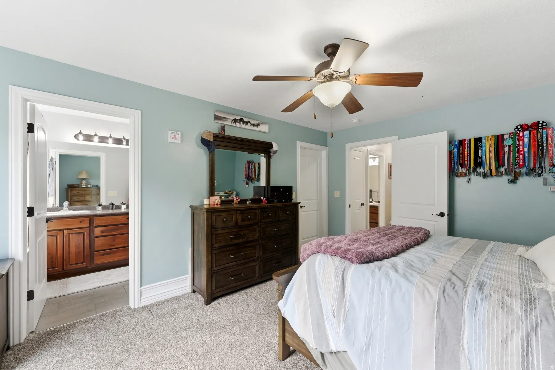 Bedroom featuring ensuite bath, light colored carpet, and ceiling fan