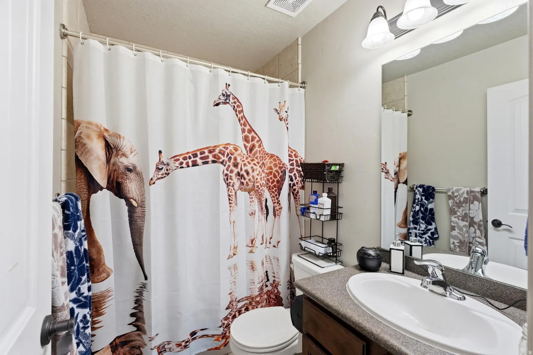 Full bathroom with vanity, curtained shower, and a textured ceiling