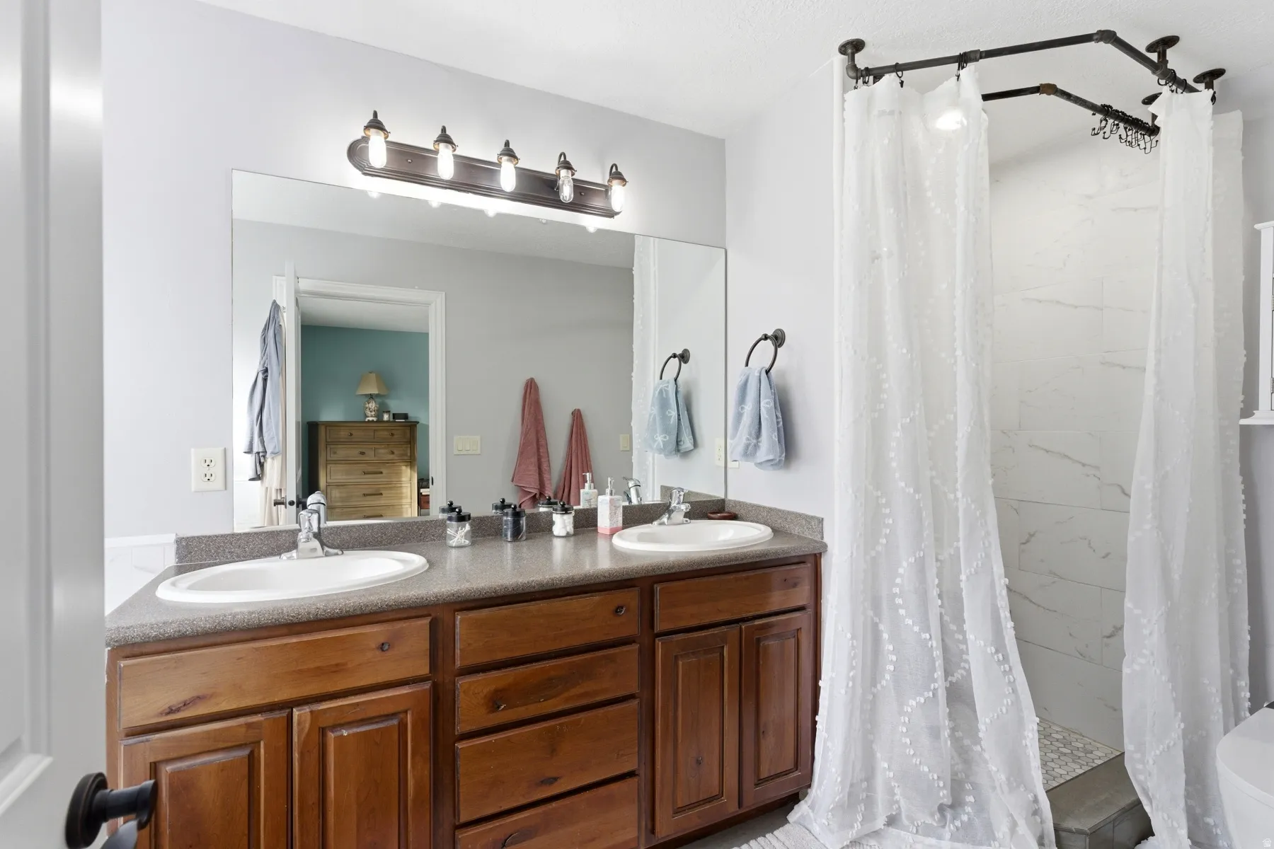Full bath with double vanity and a shower stall