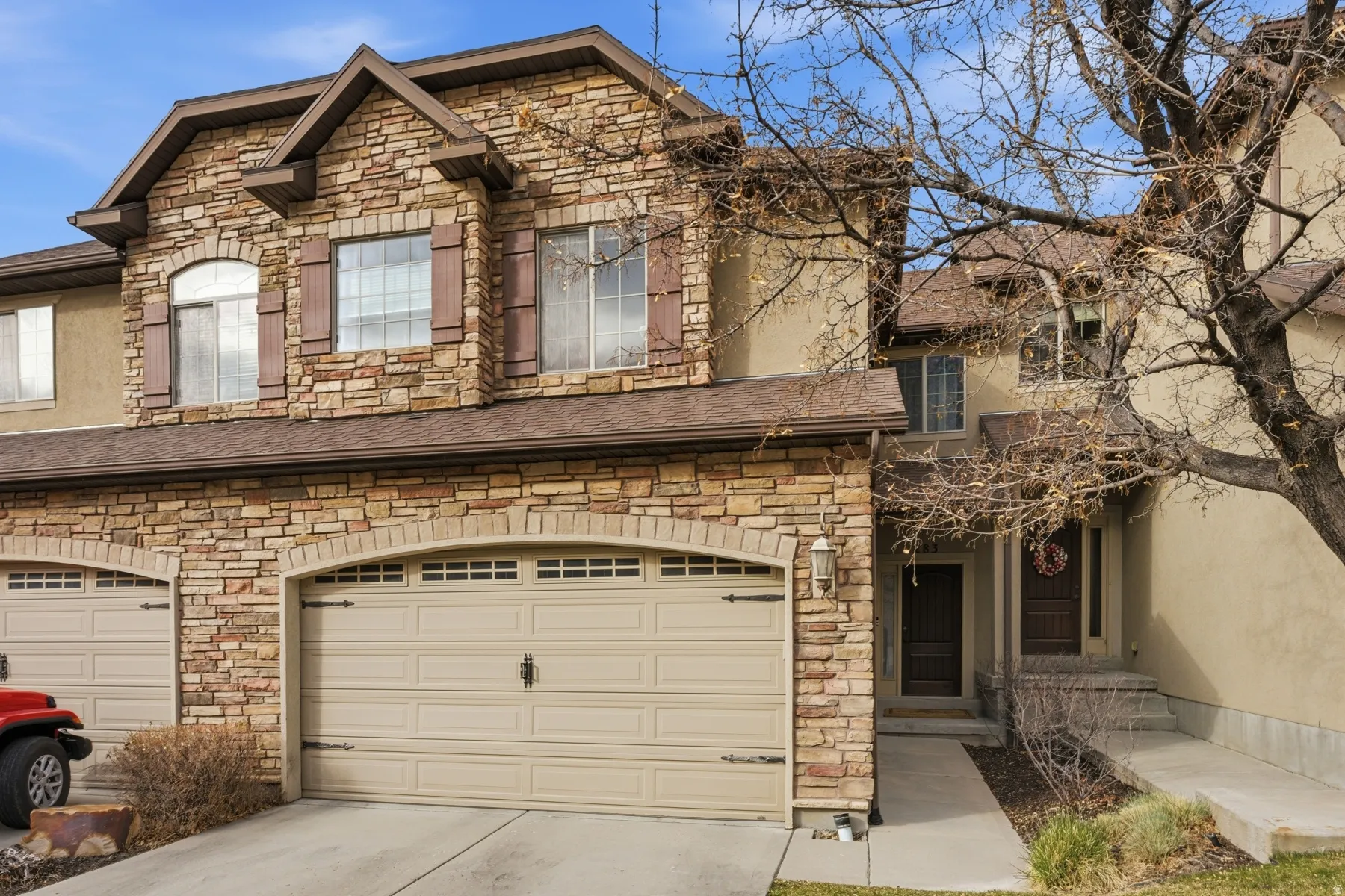 View of front of house with stone siding, driveway, and stucco siding