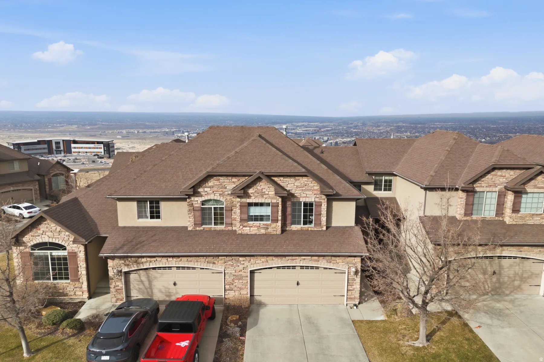 French provincial home with stone siding, a garage, roof with shingles, and driveway