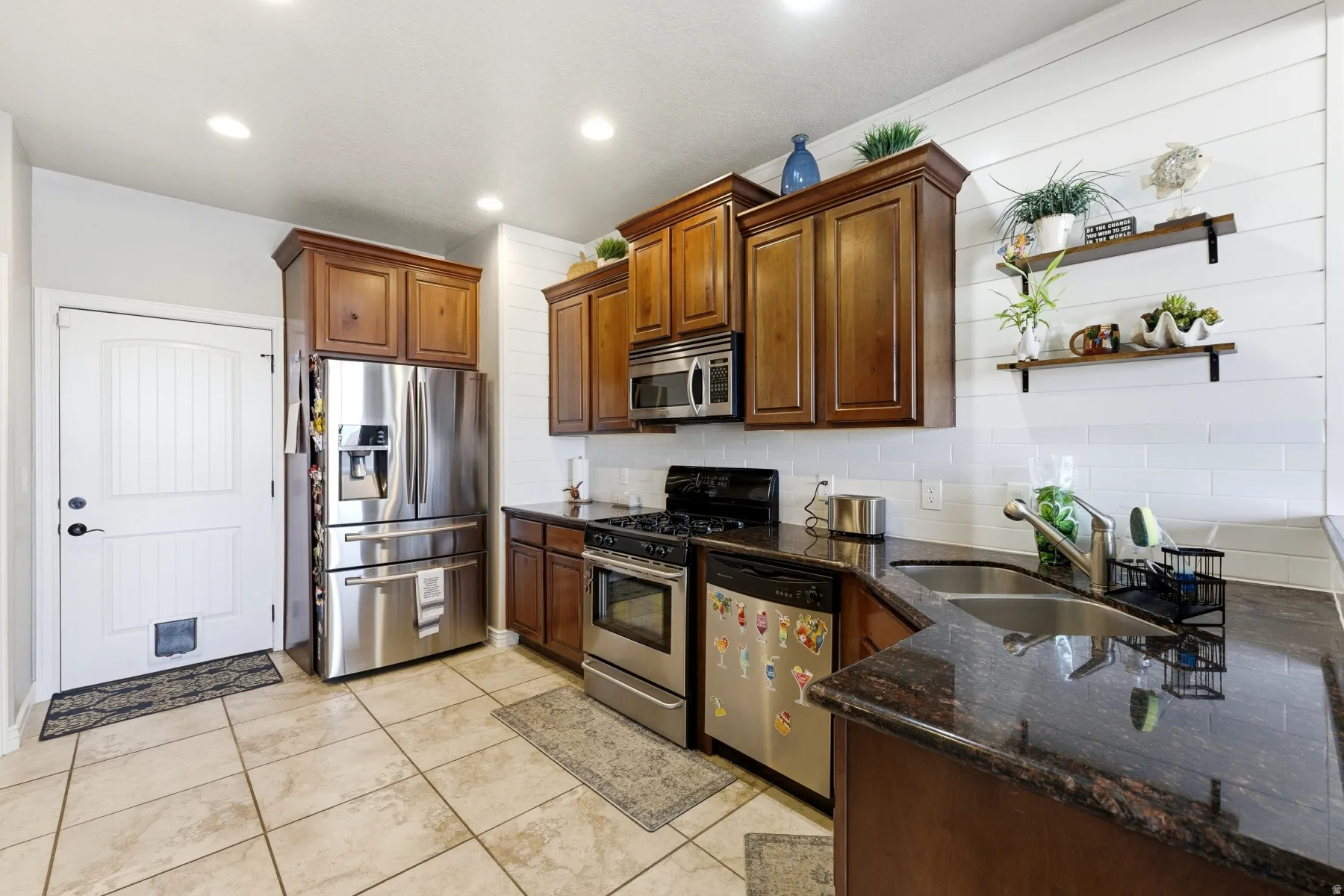 Kitchen with stainless steel appliances, backsplash, dark stone counters, open shelves, and recessed lighting