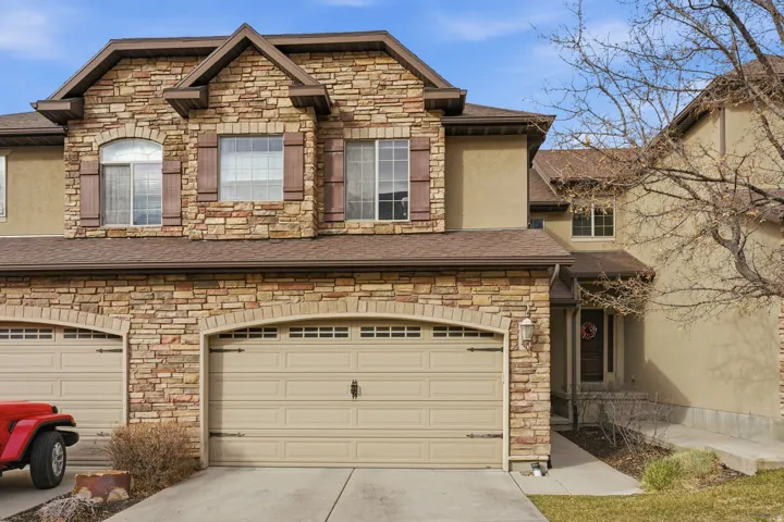 View of front of house featuring stone siding and a shingled roof
