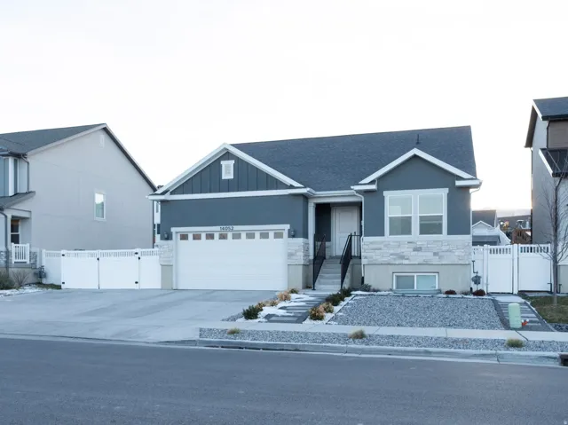 View of front of property with a gate, driveway, a garage, and board and batten siding