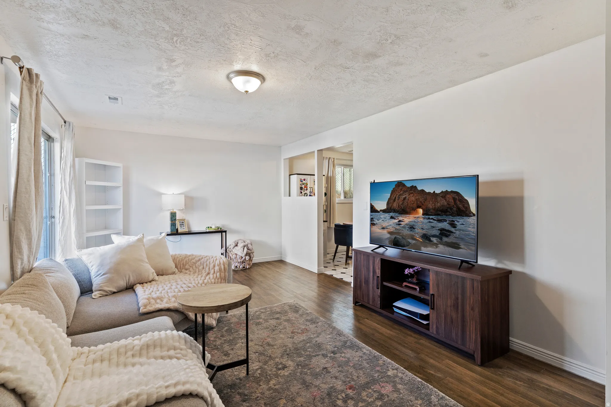 Living area featuring dark wood-style floors and a textured ceiling