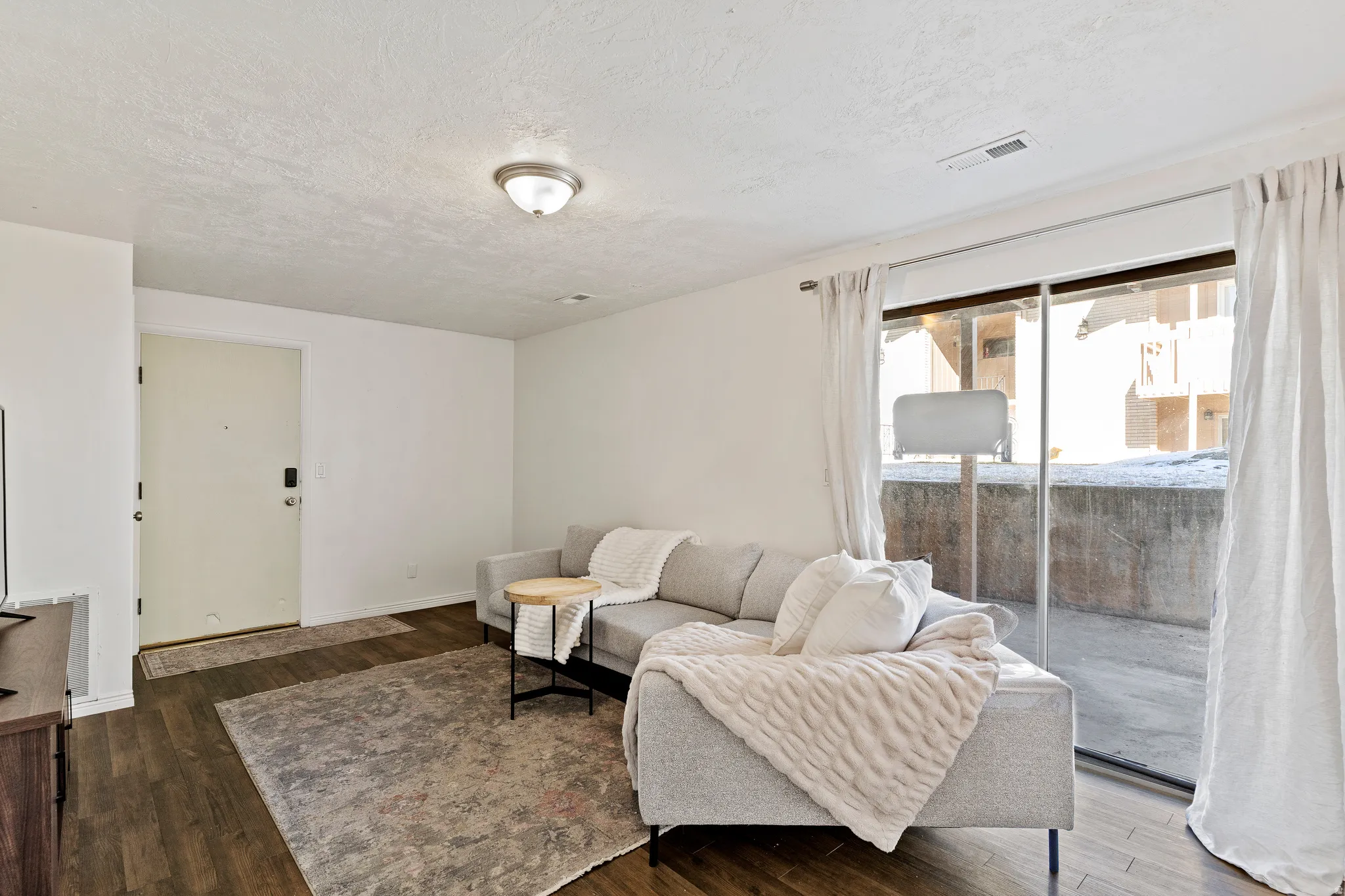 Living room with dark wood-type flooring and a textured ceiling