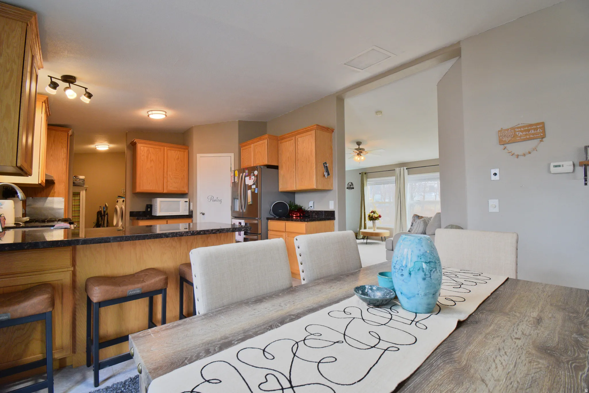 Kitchen with a kitchen bar, stainless steel appliances, a ceiling fan, white microwave, and a peninsula