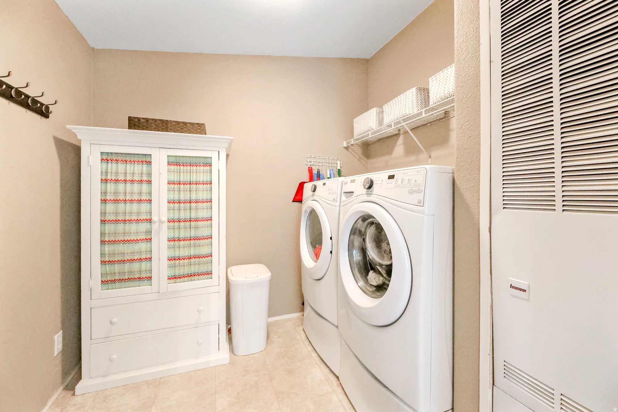 Laundry room featuring a heating unit, washer and dryer, and light tile patterned floors