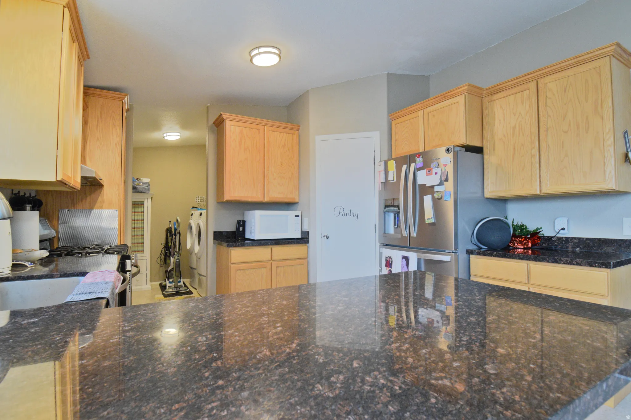 Kitchen with light brown cabinetry, dark Marble countertops, appliances with stainless steel finishes, and a peninsula