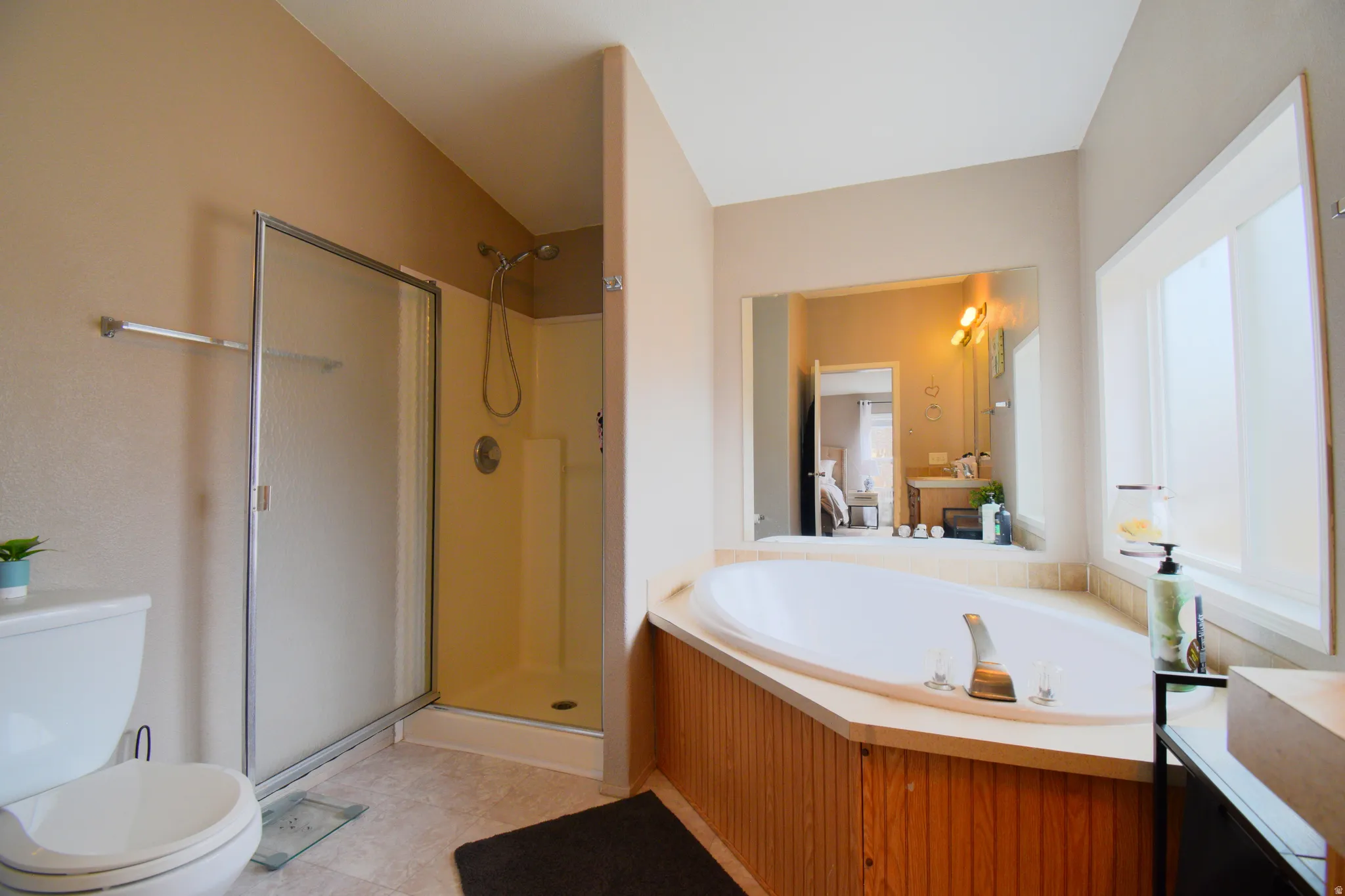 Full bath featuring a garden tub, a stall shower, vanity, light tile patterned floors, and ensuite bath