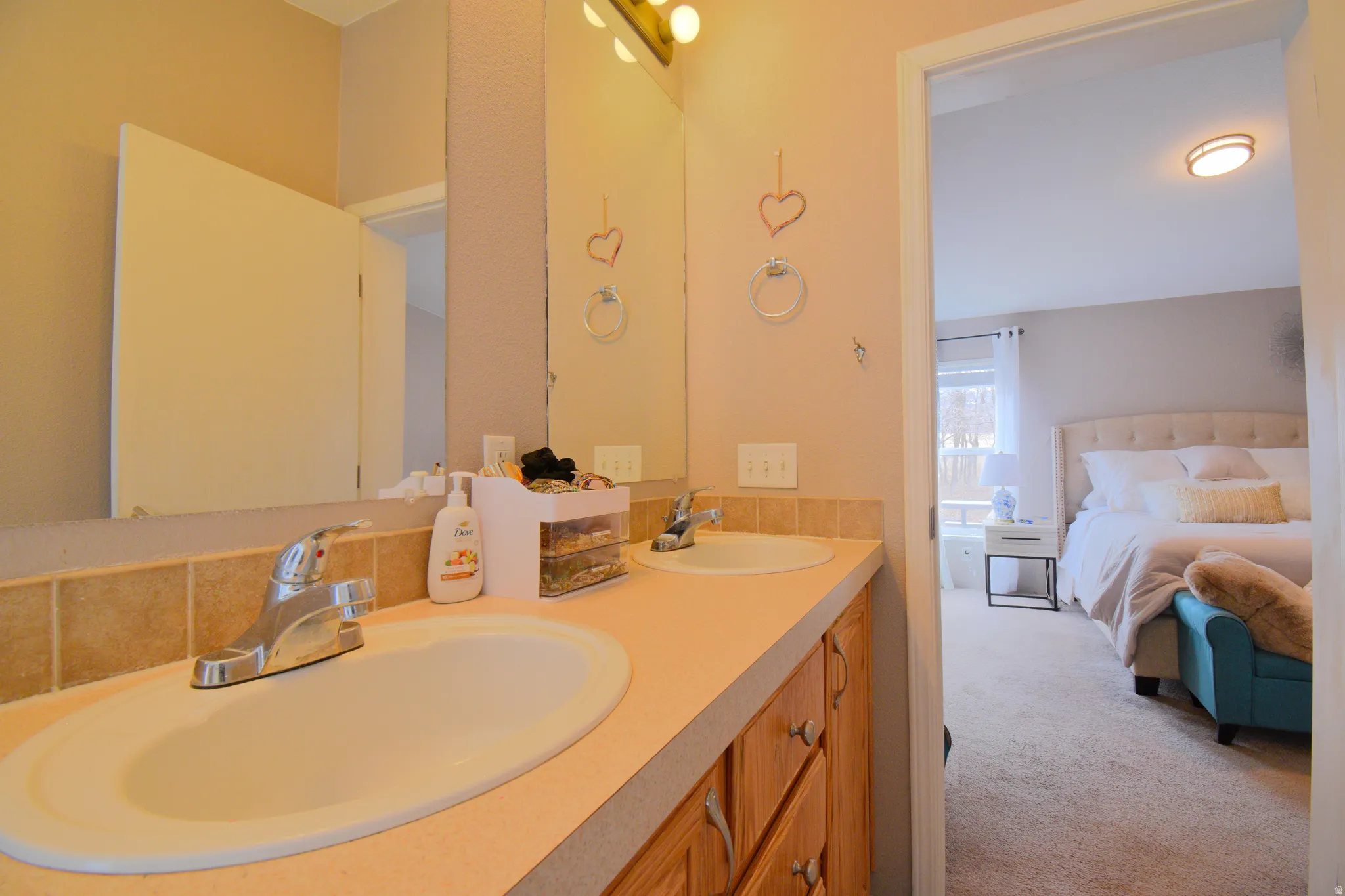 Ensuite bathroom with double vanity and light colored carpet