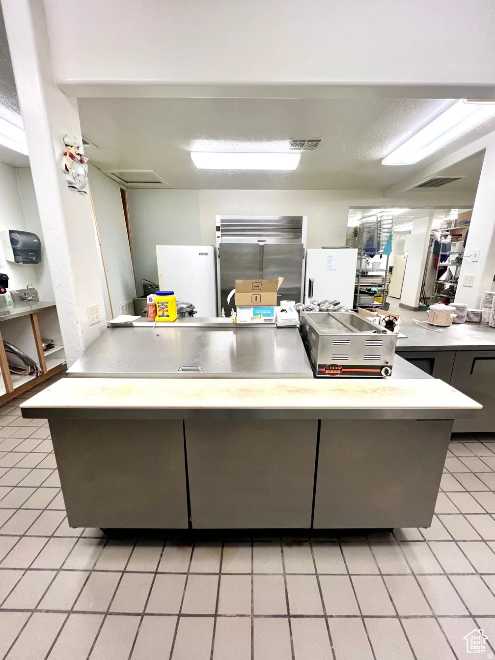 Kitchen featuring light countertops, a peninsula, gray cabinets, and freestanding refrigerator