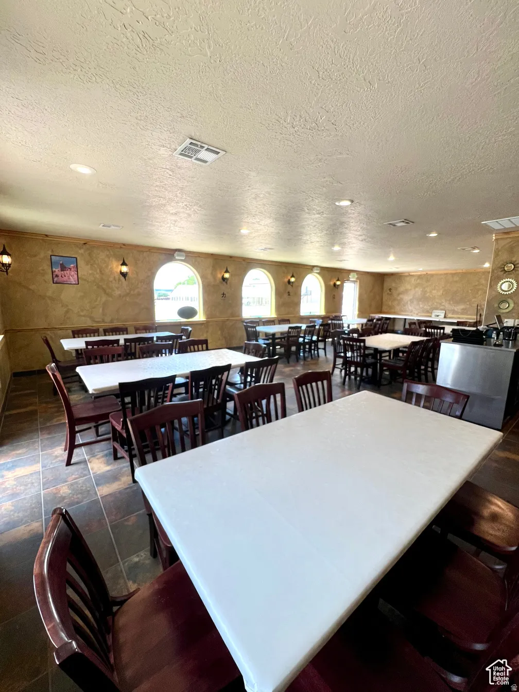 Dining space featuring a textured ceiling and dark stone finish flooring