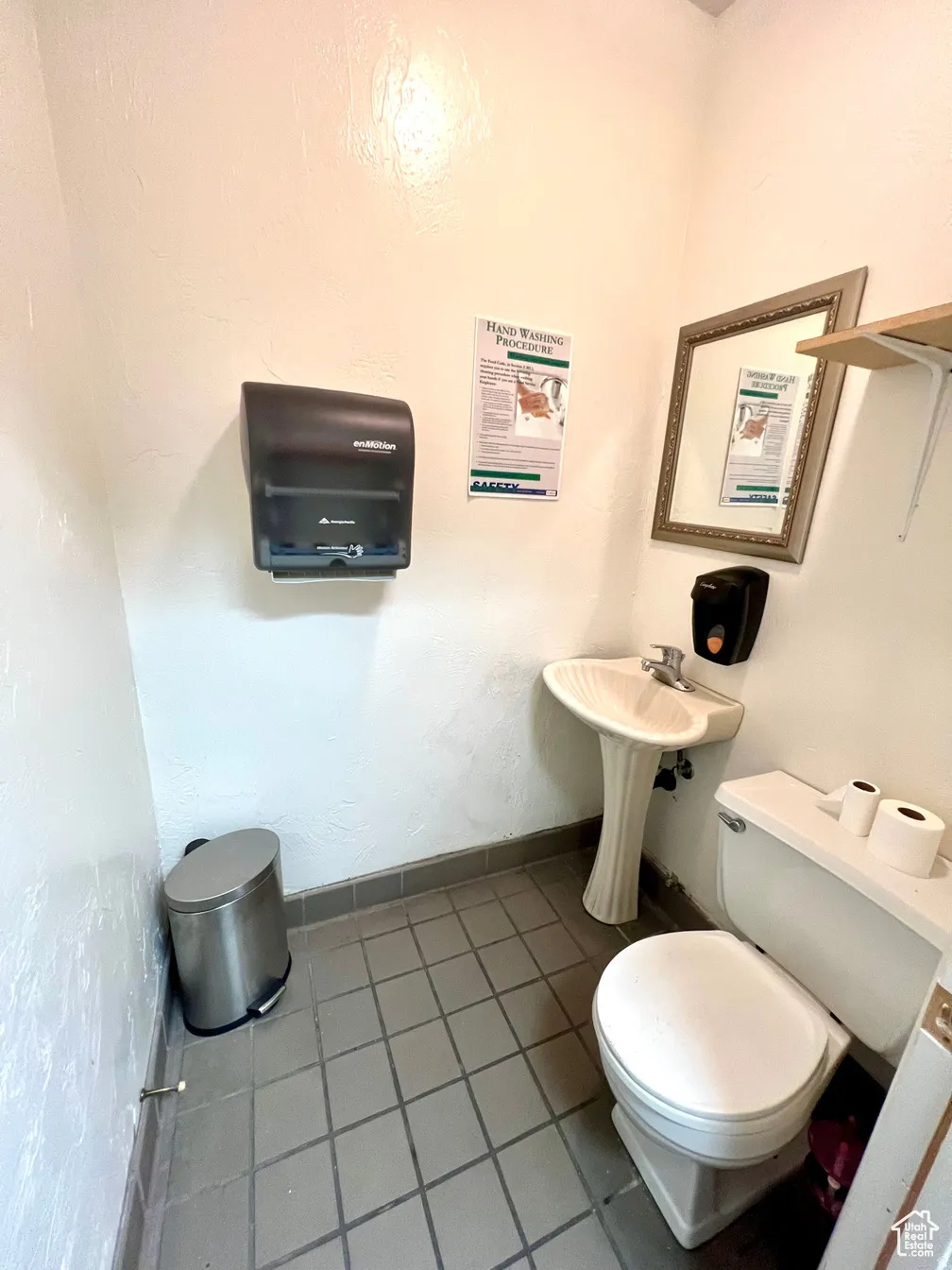 Half bathroom featuring toilet and a textured wall