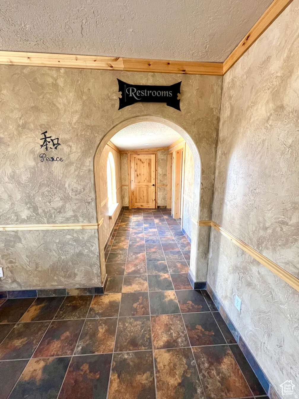 Corridor featuring a textured ceiling, ornamental molding, and arched walkways