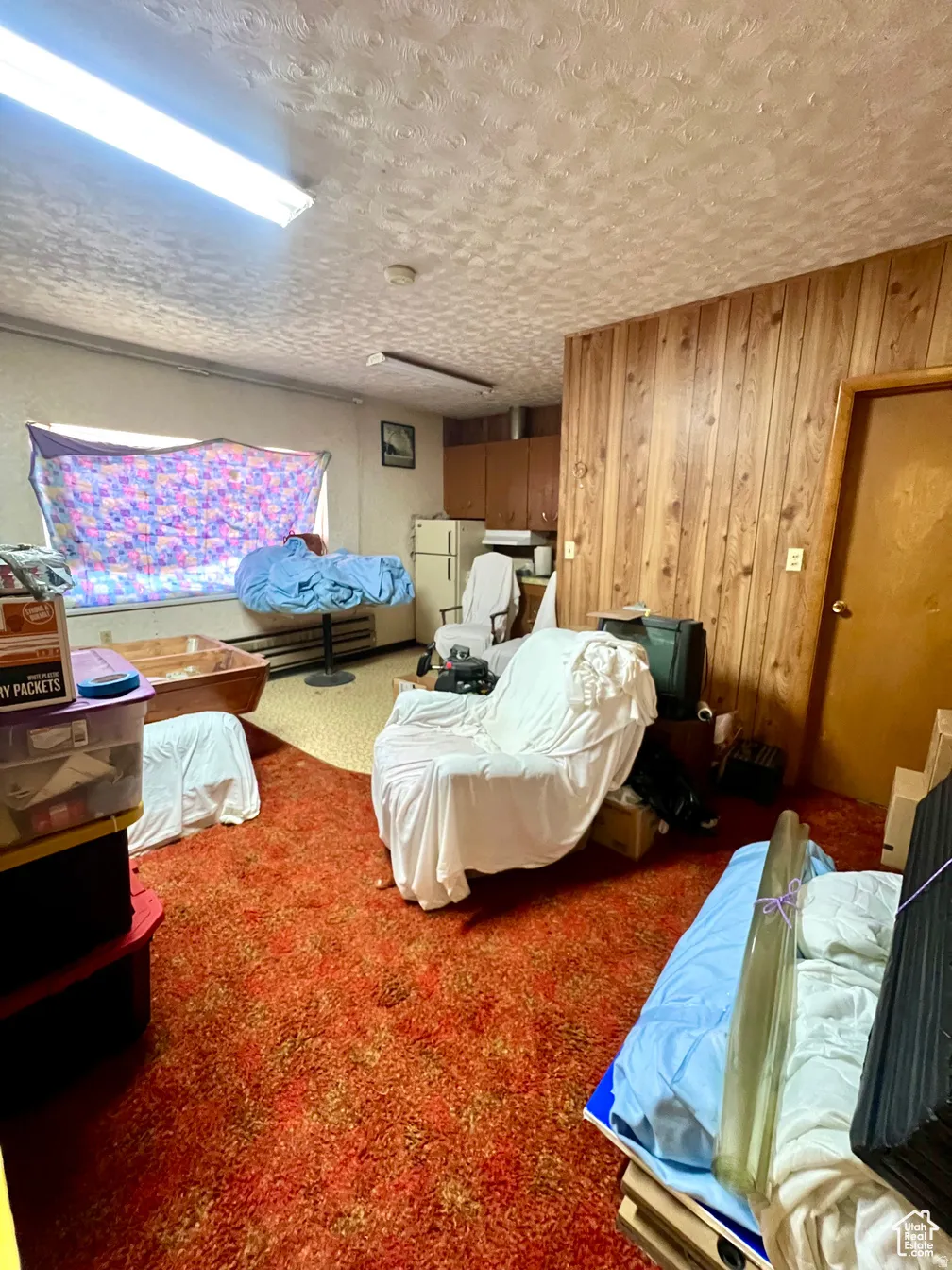 Bedroom featuring carpet floors, freestanding refrigerator, and a textured ceiling