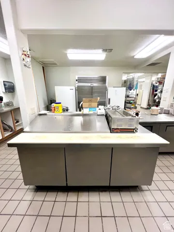 Kitchen featuring light countertops, a peninsula, gray cabinets, and freestanding refrigerator