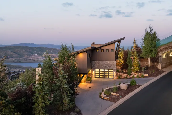 View of front facade featuring stone siding, concrete driveway, and a water and mountain view