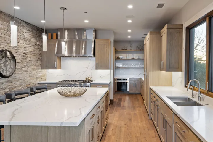 Kitchen featuring light stone counters, a kitchen island, open shelves, oven, and pendant lighting