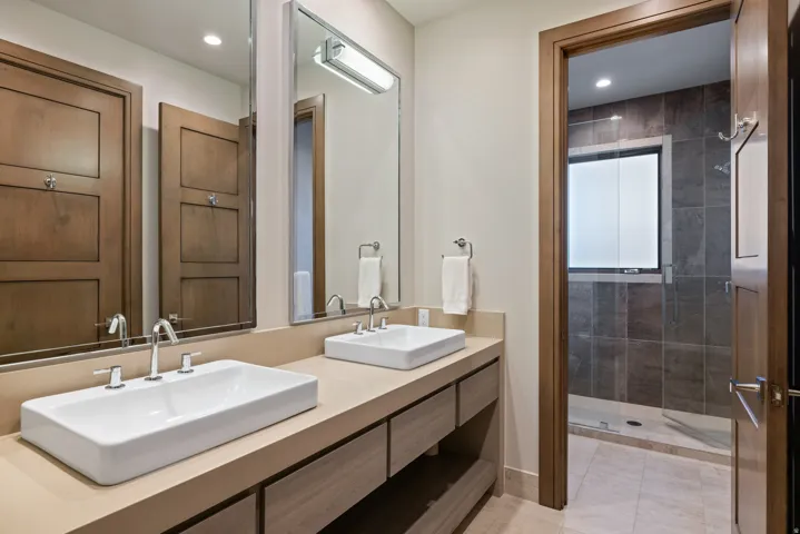 Bathroom featuring a shower stall, double vanity, and recessed lighting