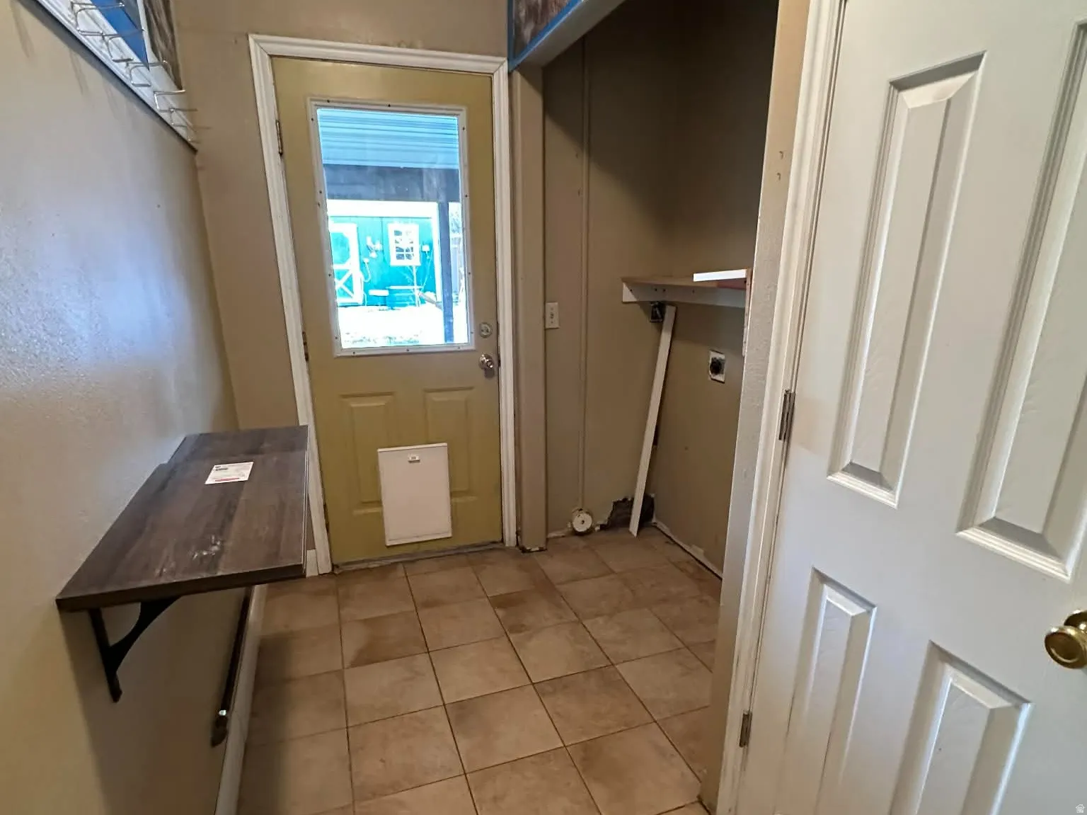 Laundry room featuring light tile patterned flooring, doggie door, and closet.