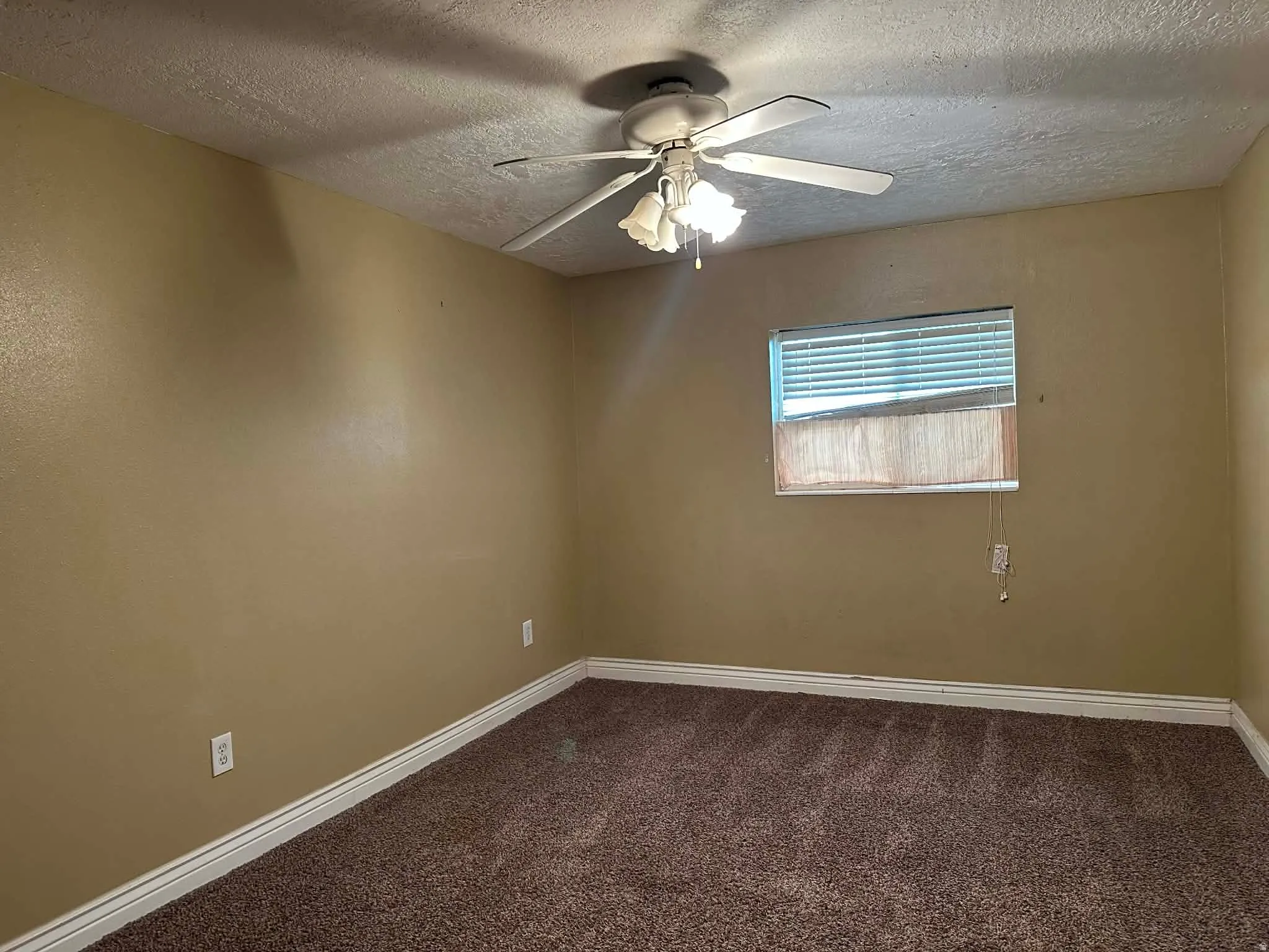 Unfurnished room with dark colored carpet, a textured ceiling, and a ceiling fan