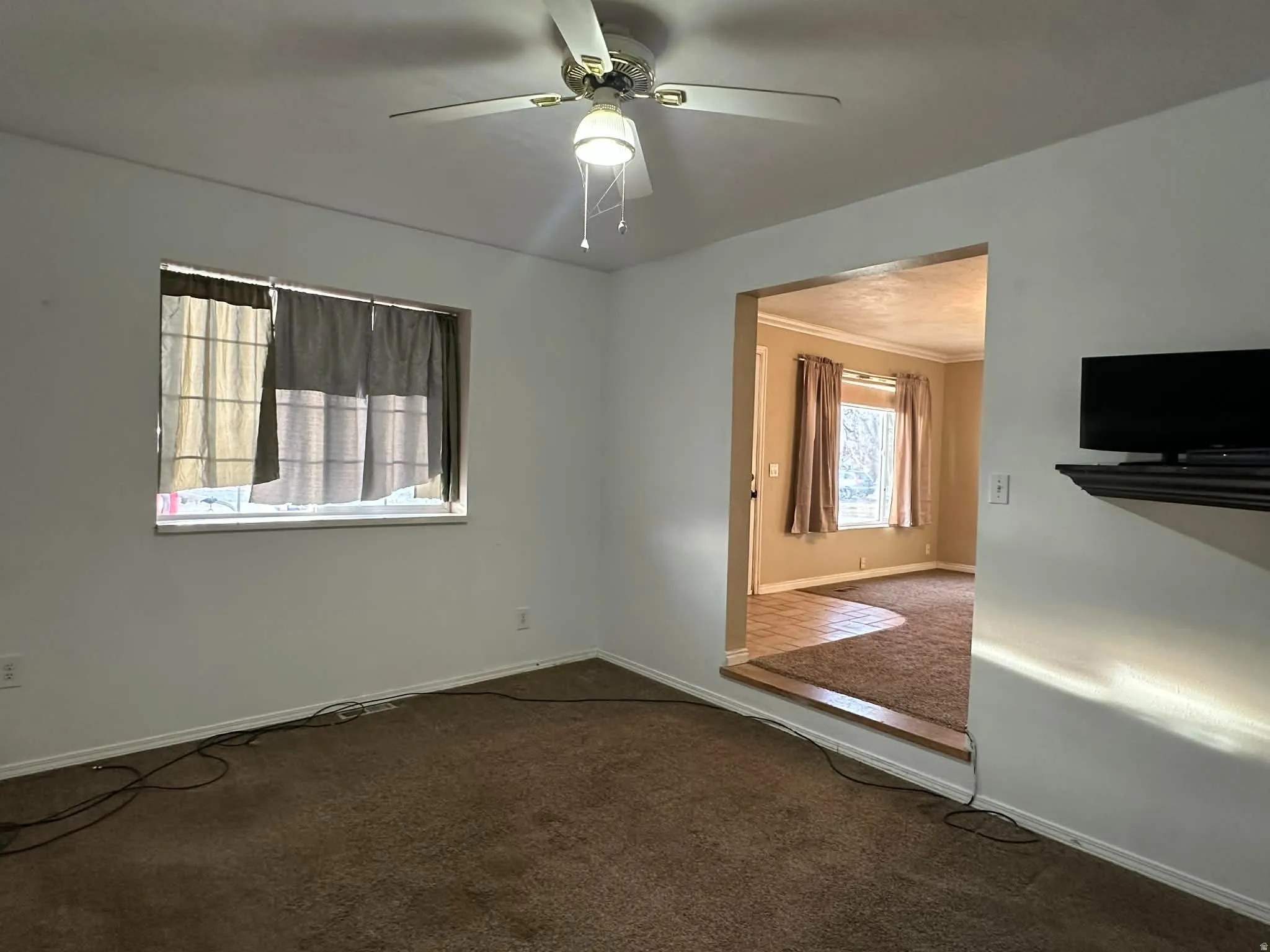 Spare room featuring dark colored carpet, a ceiling fan, and ornamental molding
