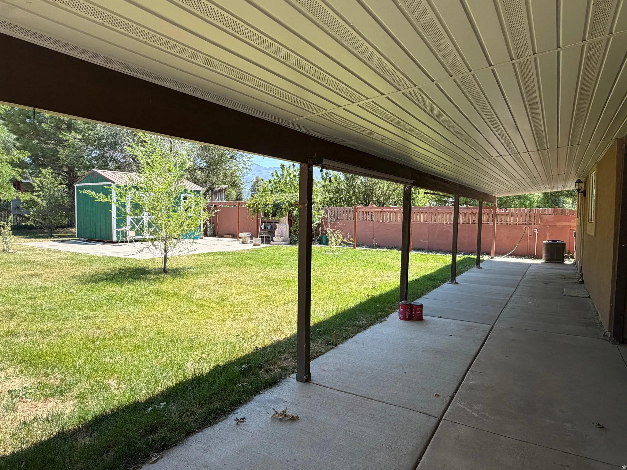Expansive covered patio featuring a full-length concrete surface and a slatted ceiling