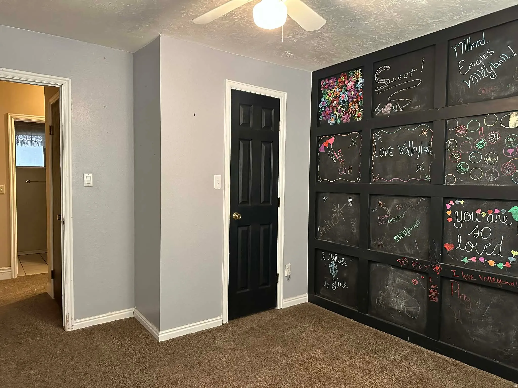 Unfurnished room with dark carpet, a textured ceiling, and a ceiling fan