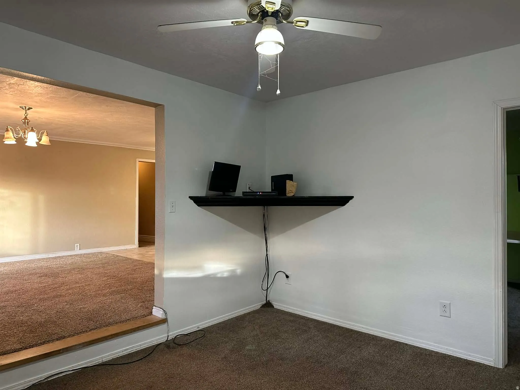 Empty room featuring carpet flooring, ornamental molding, a chandelier, and ceiling fan