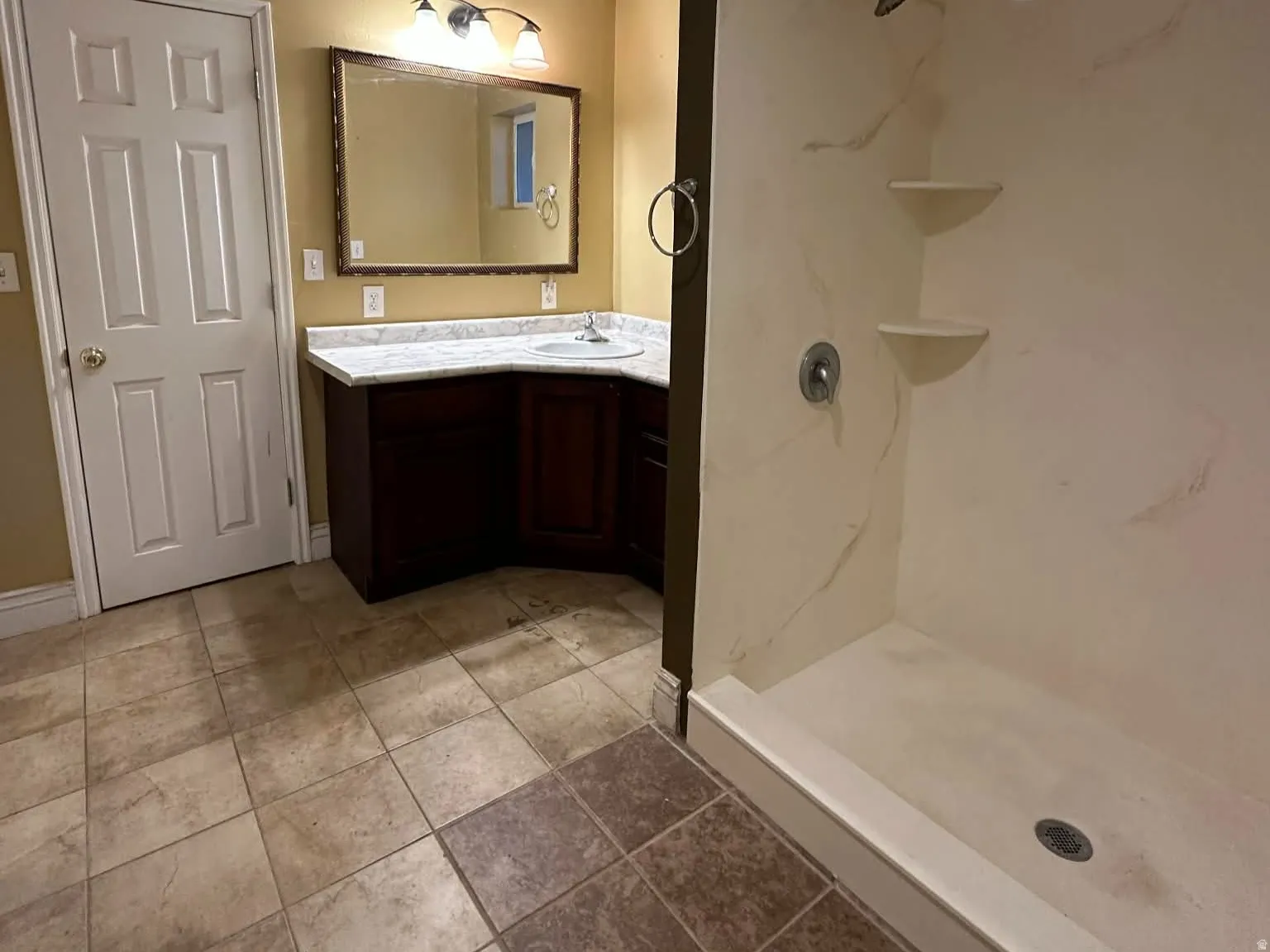 Primary bathroom featuring a corner vanity, a textured ceiling, step-in  shower, and light tile patterned floors