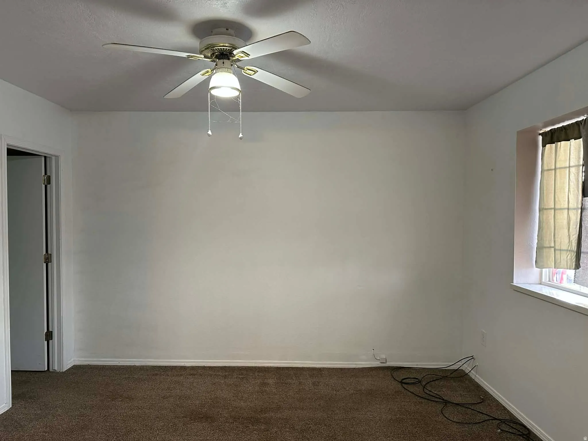 Spare room featuring dark colored carpet and ceiling fan