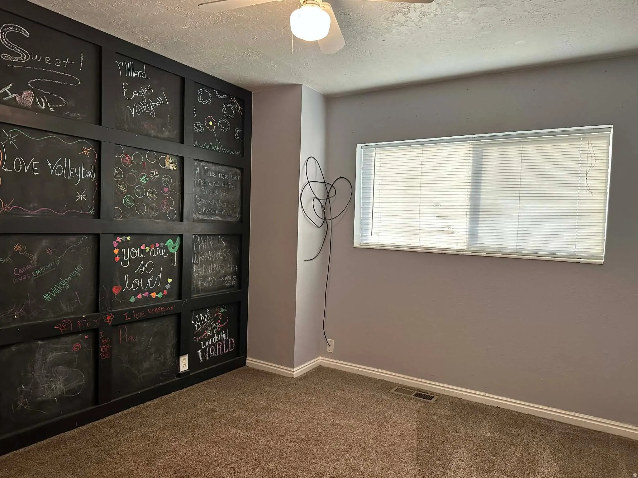 Carpeted spare room featuring a textured ceiling and ceiling fan