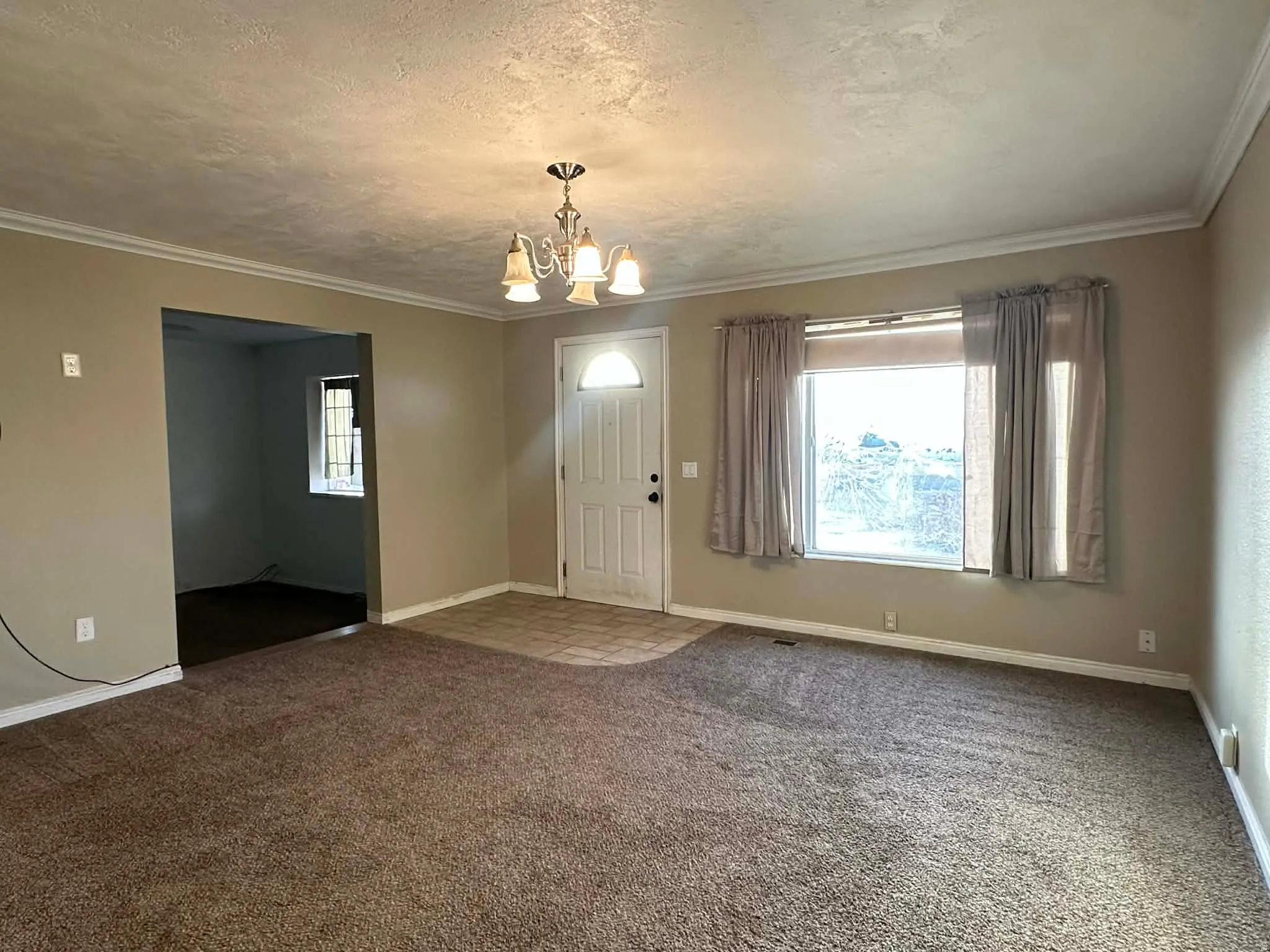 Carpeted foyer with a chandelier, a textured ceiling, and ornamental molding