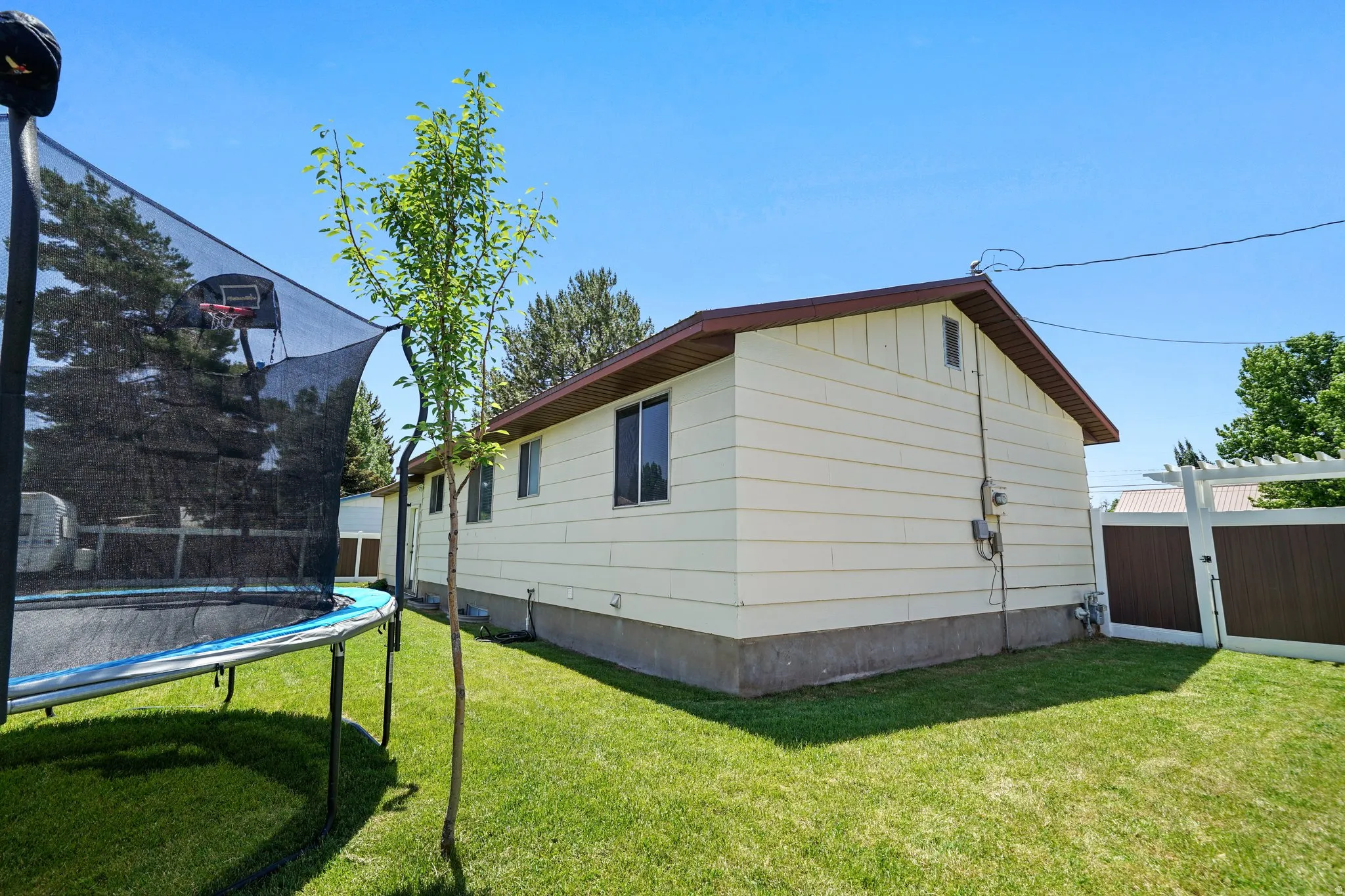 View of side of property with a trampoline, a gate, and board and batten siding