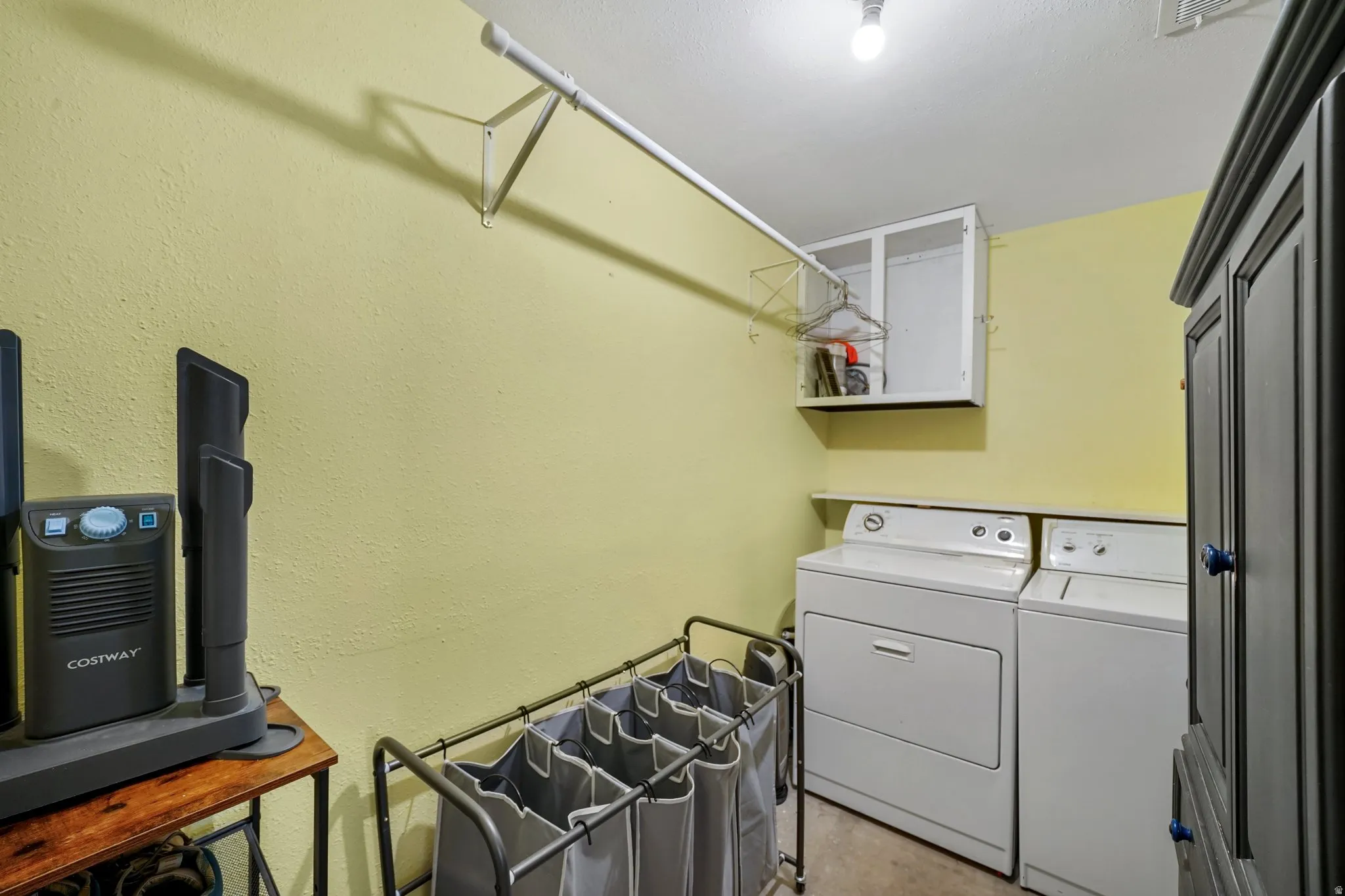 Laundry room featuring concrete flooring, independent washer and dryer, and a textured wall