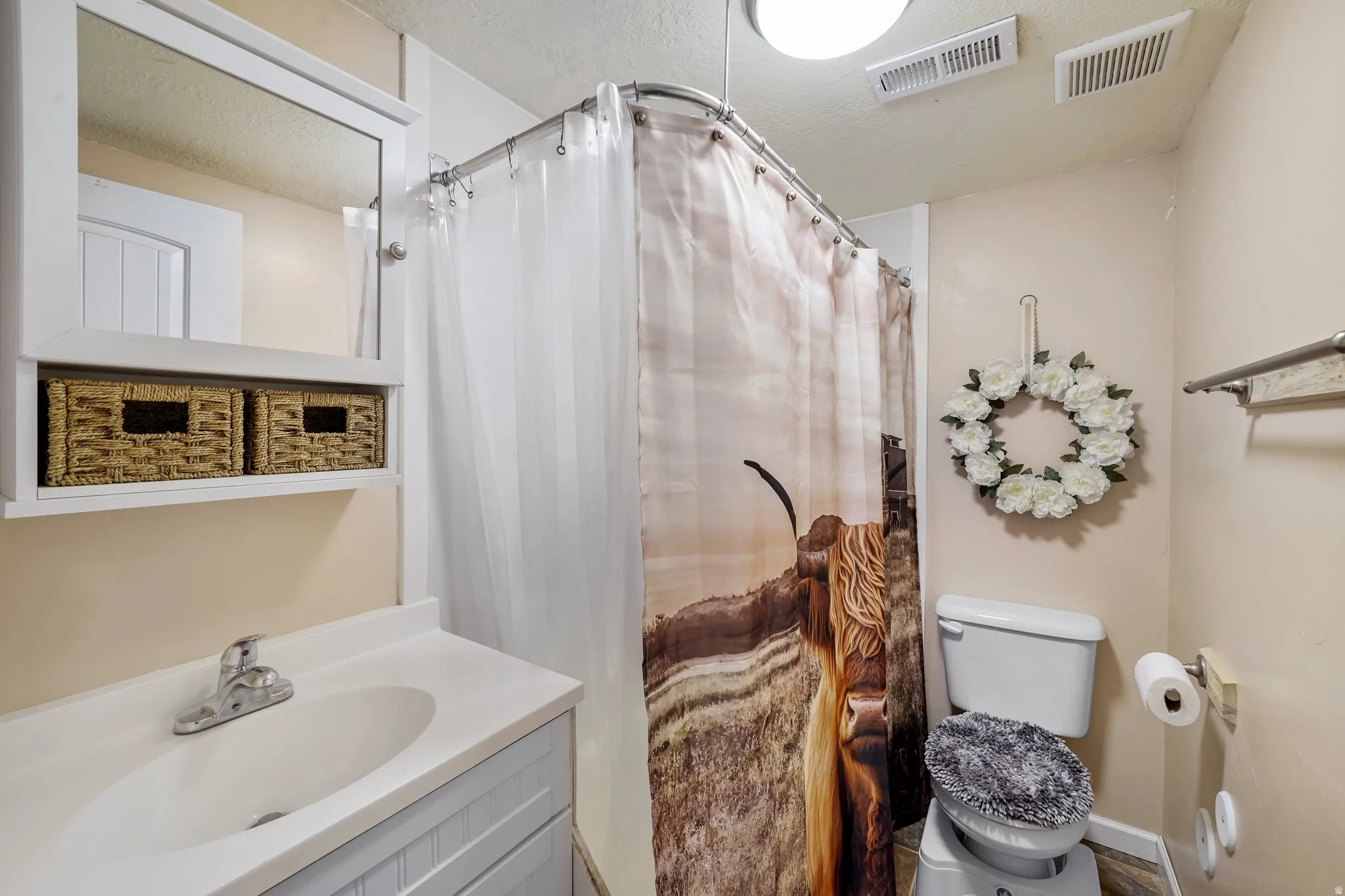 Full bathroom featuring curtained shower, vanity, and a textured ceiling