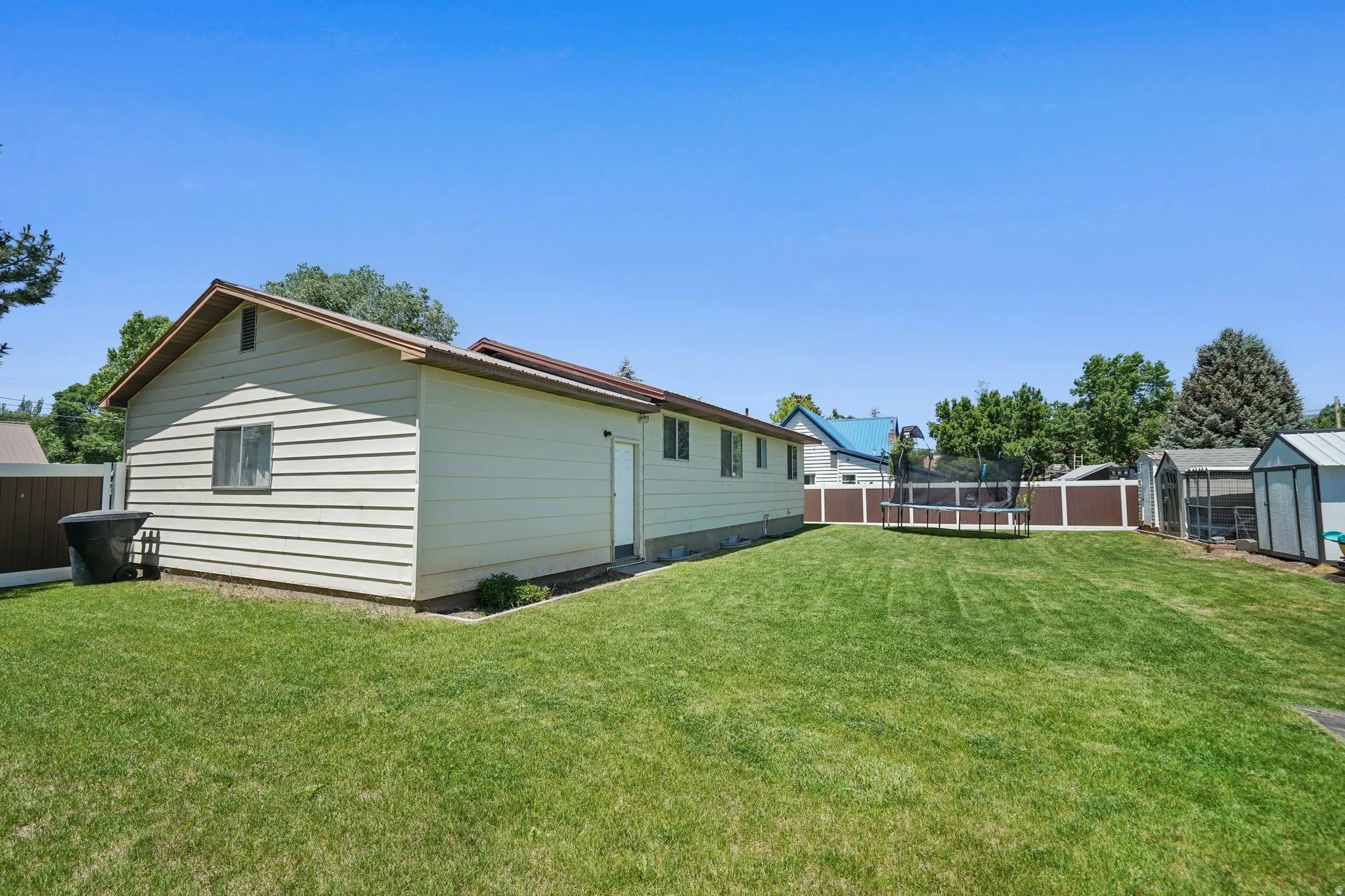 Rear view of property featuring a trampoline and an outbuilding